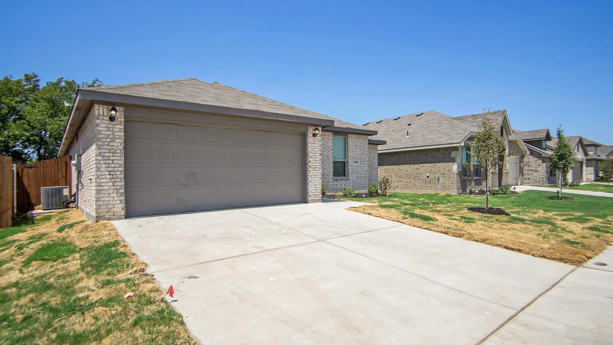 Exterior featuring light-toned brick, a multi-car driveway, and a two-car garage with a panel door