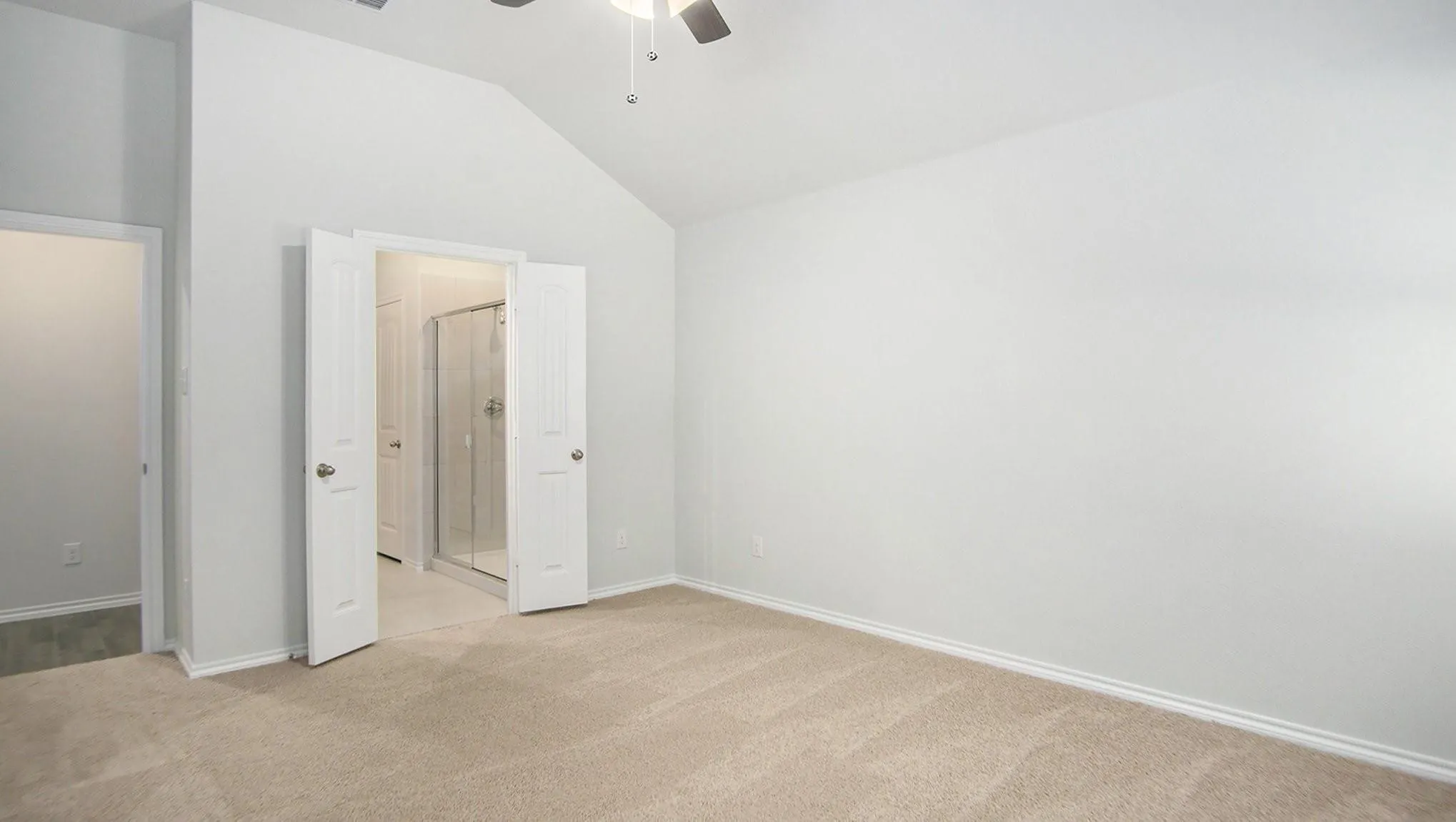 Spacious room with vaulted ceiling and neutral carpet flooring