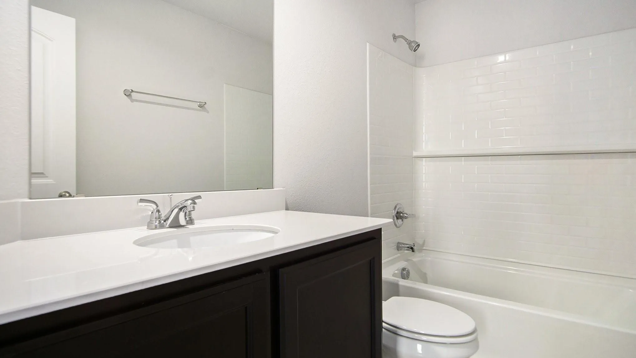 Bathroom featuring a white subway tile tub surround, chrome shower fixtures, and a white porcelain bathtub