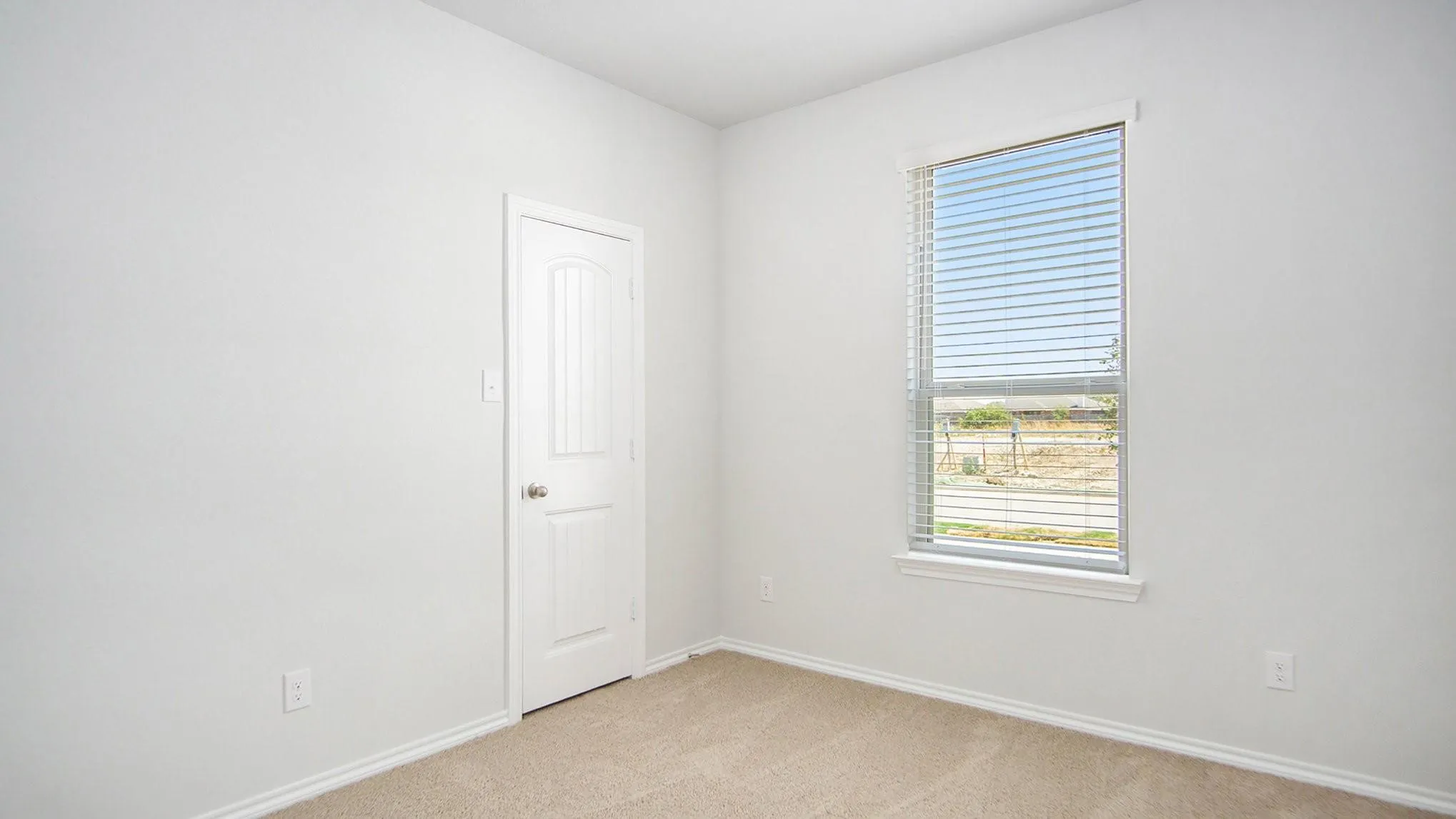 Neutral wall finishes with a single window featuring blinds