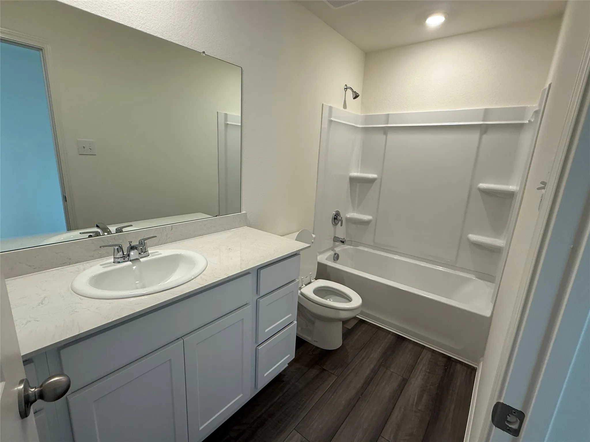 Full bathroom featuring a white vanity with an integrated sink, a light-colored countertop, and a white tub with a shower fixture
