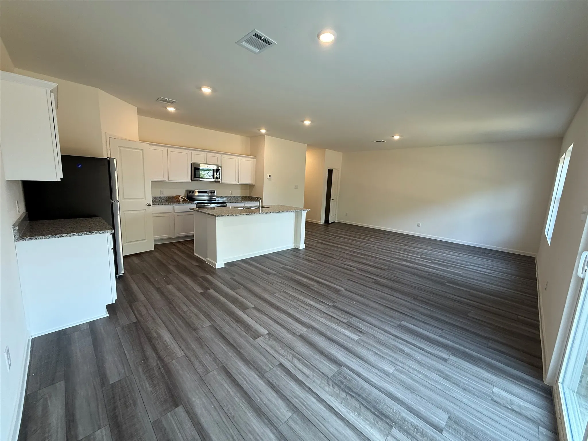 Open-concept living space featuring wood-finish flooring, recessed lighting, and ample natural light
