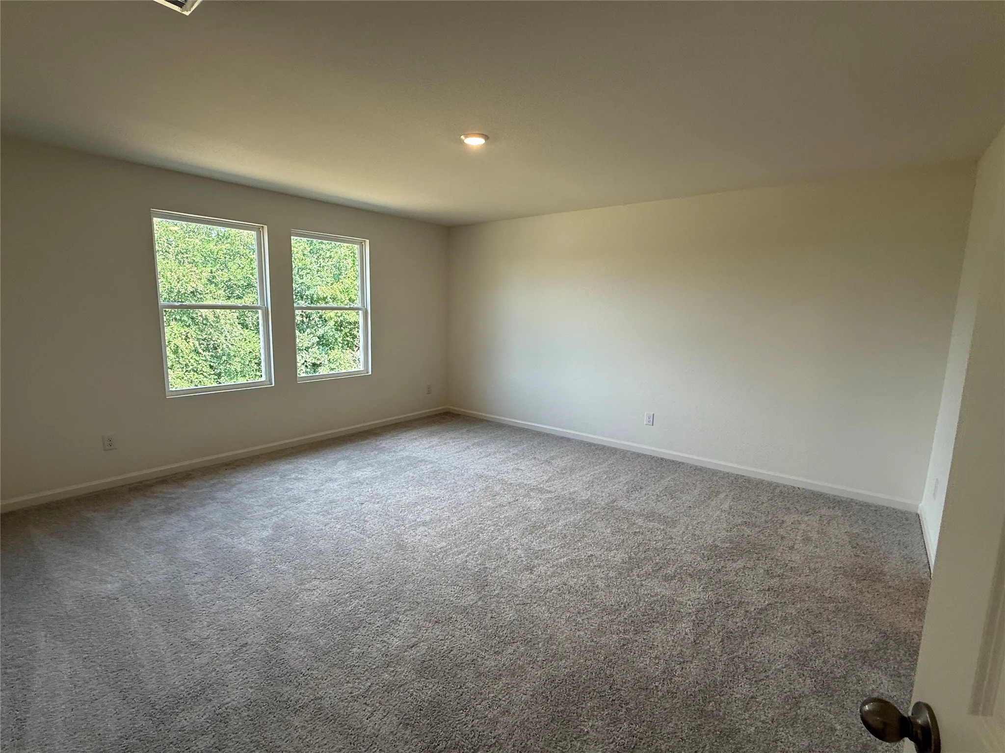 Expansive room featuring two windows, neutral wall tones, recessed lighting, and grey patterned carpeting