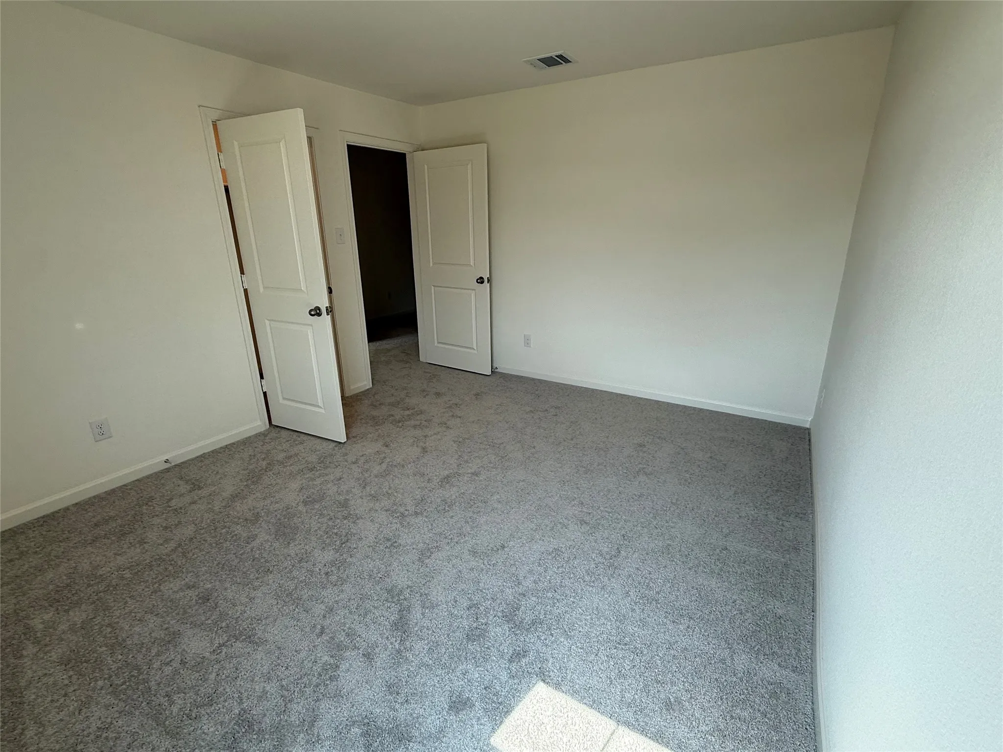 Gray carpeted flooring, white walls, and white paneled doors