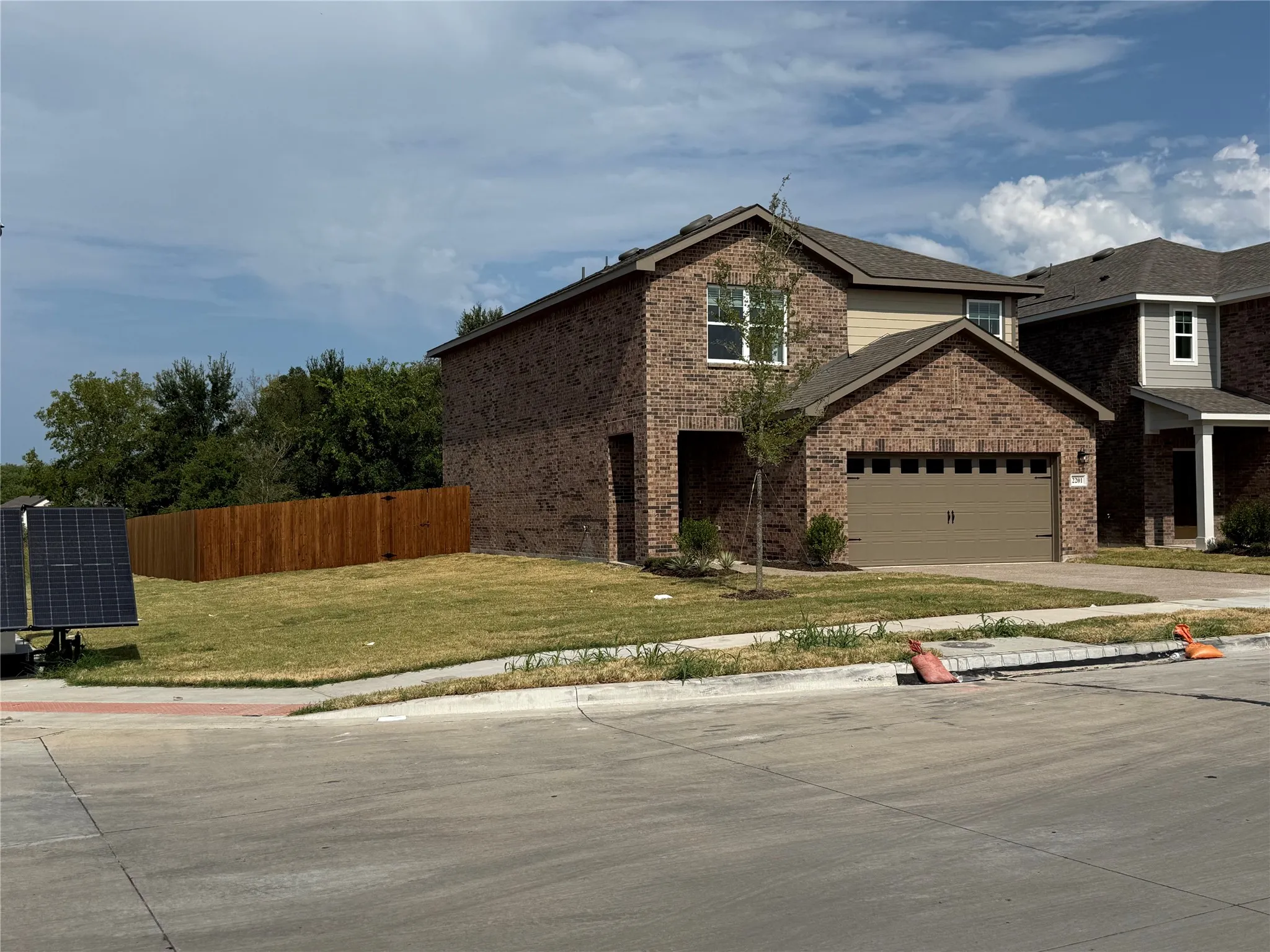 Brick exterior with a detached two-car garage, brown wood fencing, and a mature tree