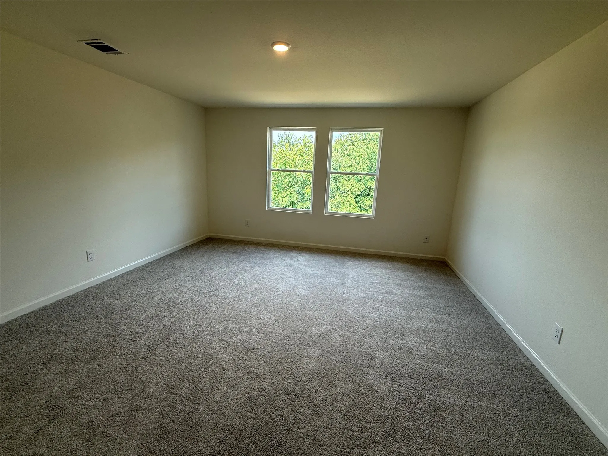 Neutral wall paint, recessed ceiling lighting, two windows, and gray carpet