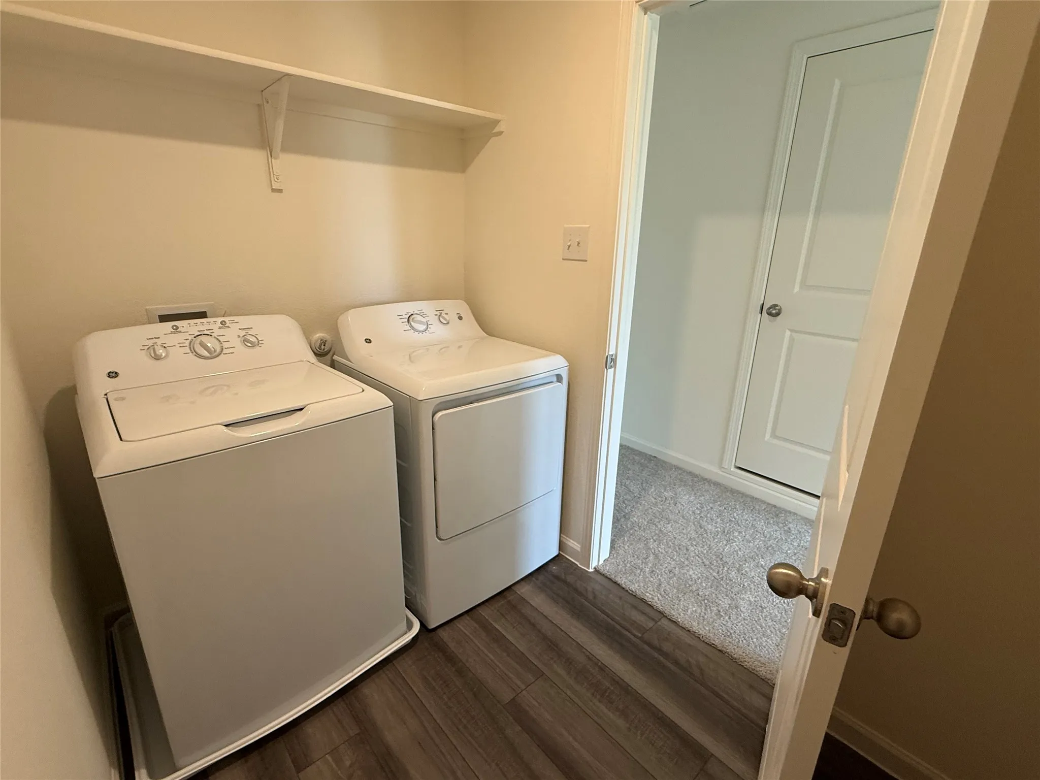 Dedicated laundry area featuring a built-in shelving unit, wood-finish flooring, and light-toned walls