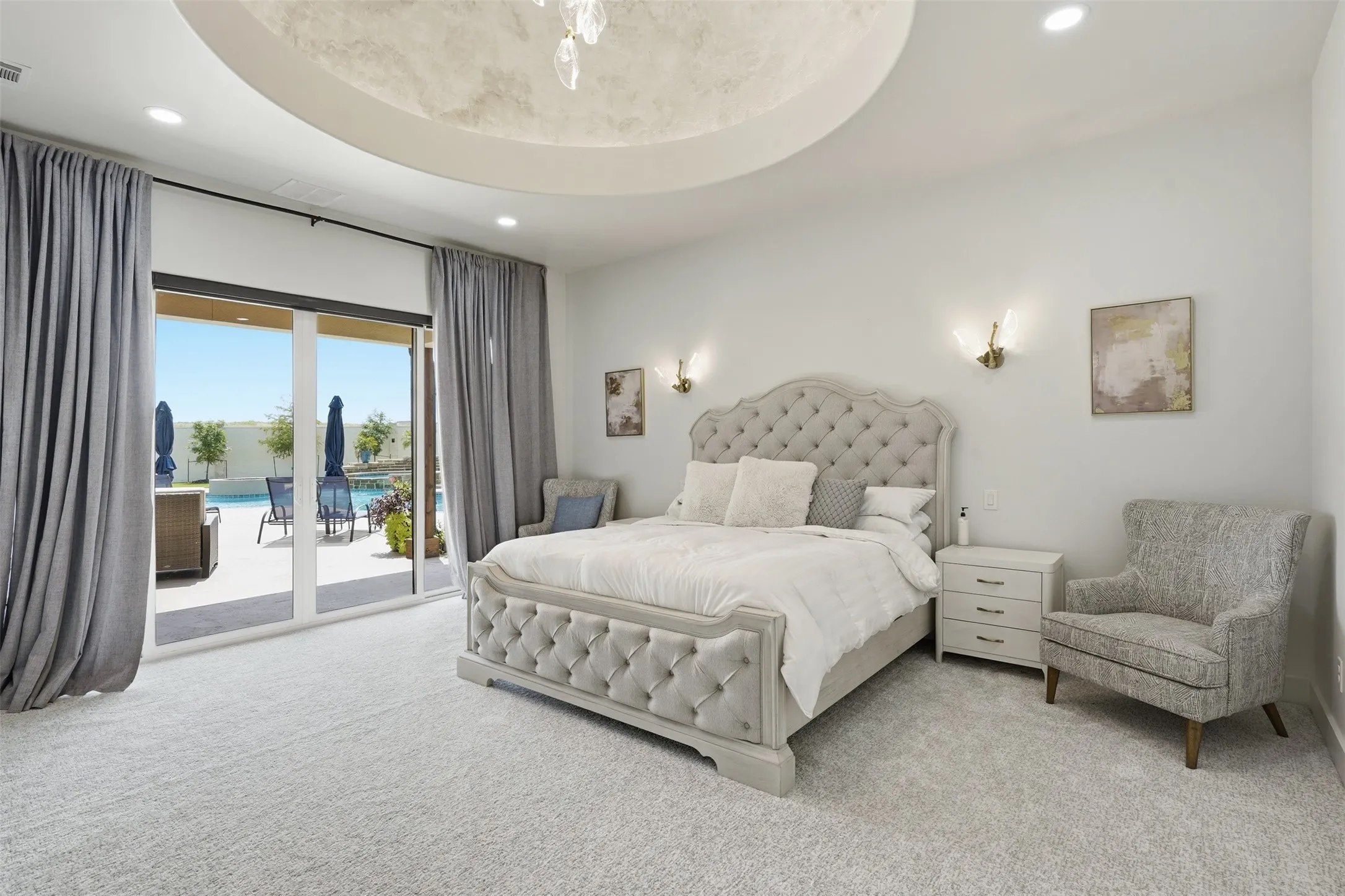 Luxurious primary bedroom suite featuring a tufted upholstered bed frame, soft-close nightstands with integrated lighting, and plush carpeting throughout