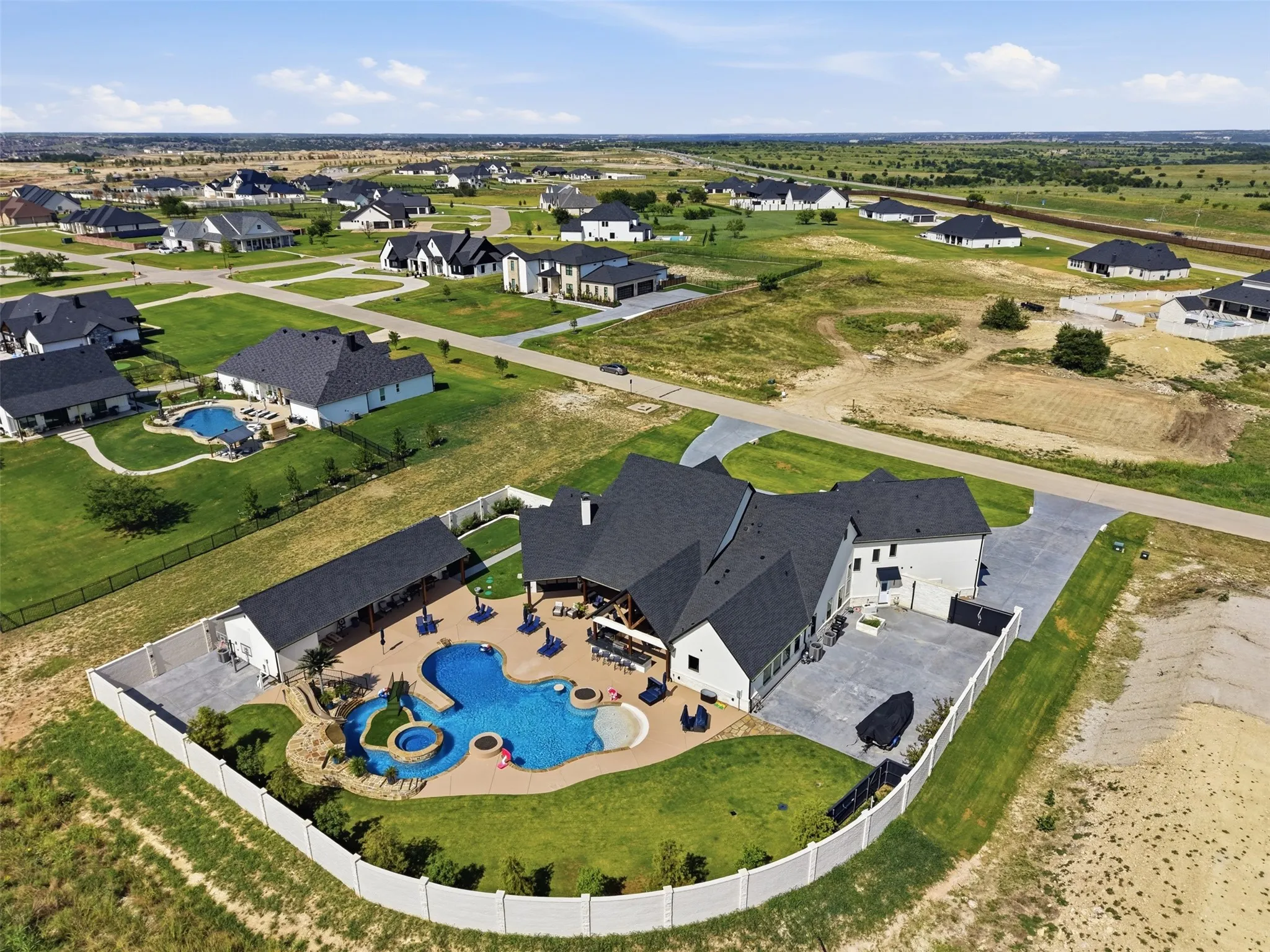 Expansive backyard featuring a free-form swimming pool, integrated spa, and an outdoor covered patio with built-in bar