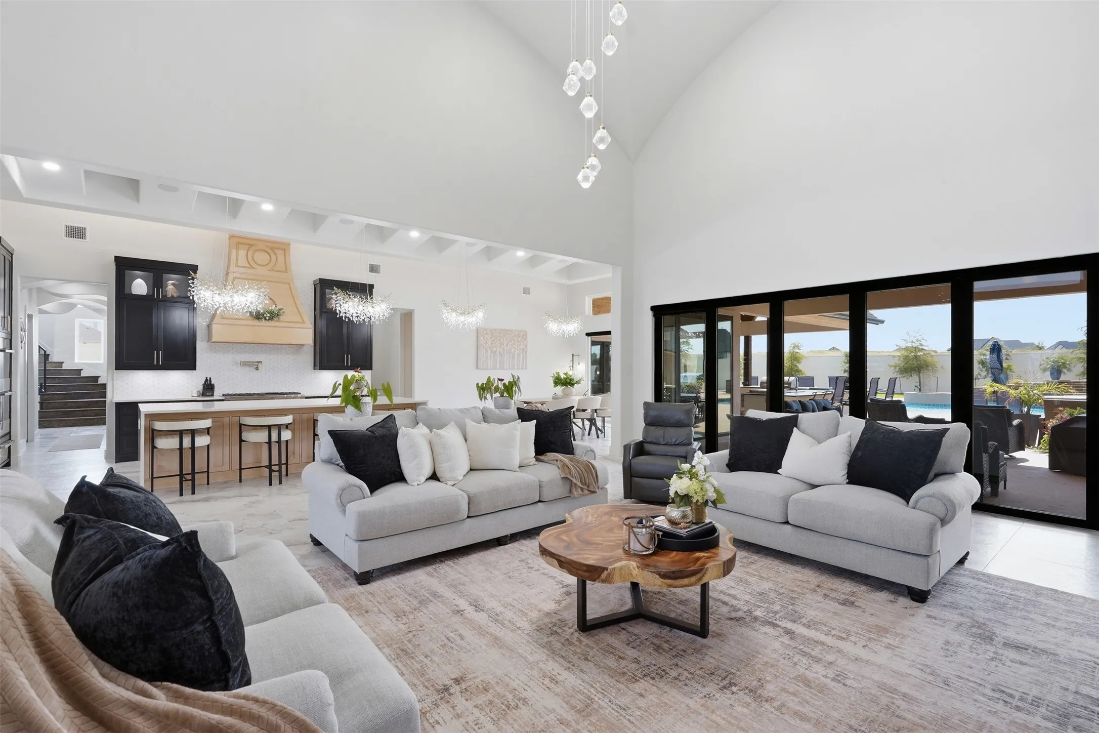 Vaulted ceiling, full wall sliding glass doors, kitchen island with seating, dark wood cabinetry, and a coffered ceiling