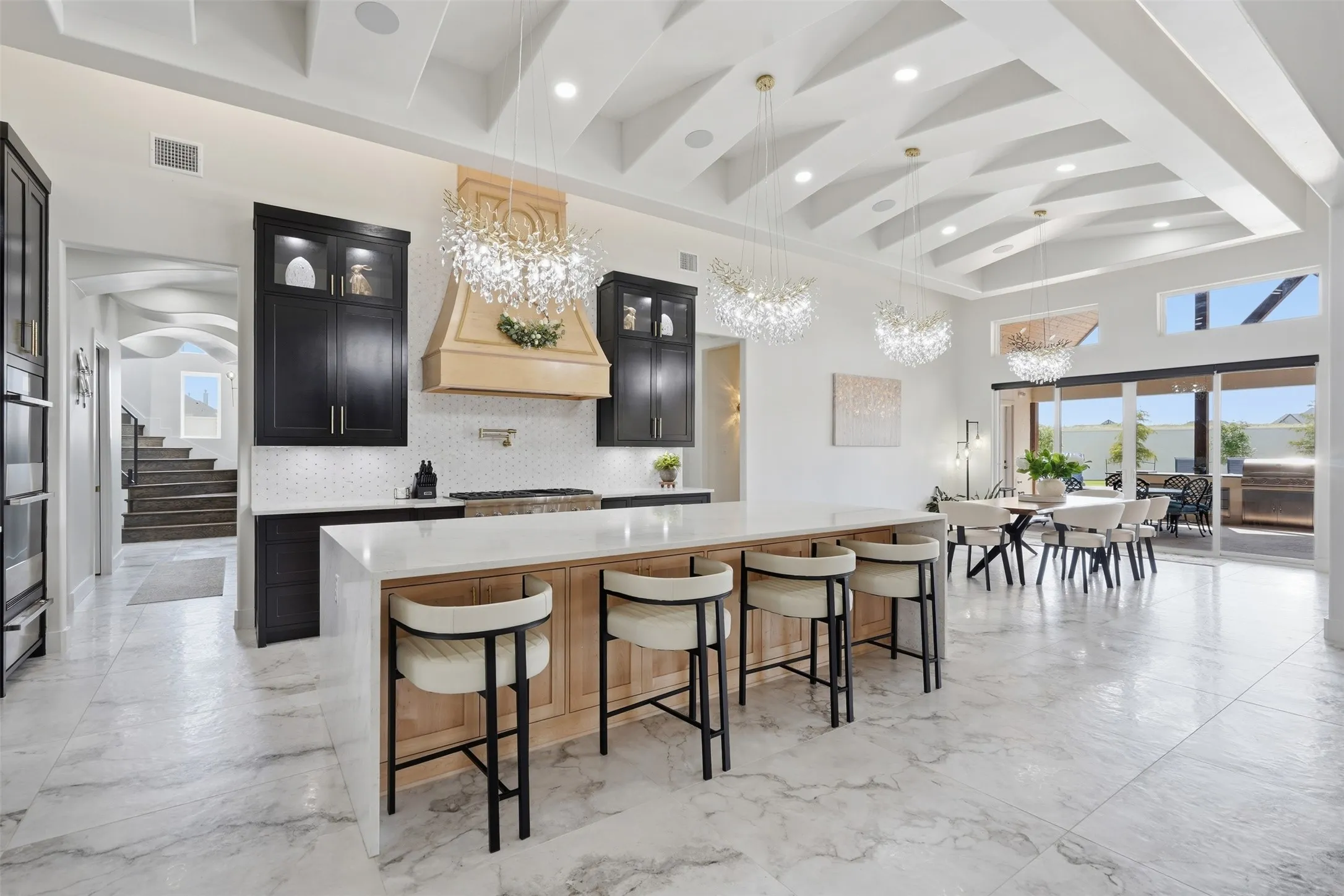 Spacious open-concept interior featuring light wood cabinetry, a large kitchen island with a light-toned countertop, and light-toned flooring throughout
