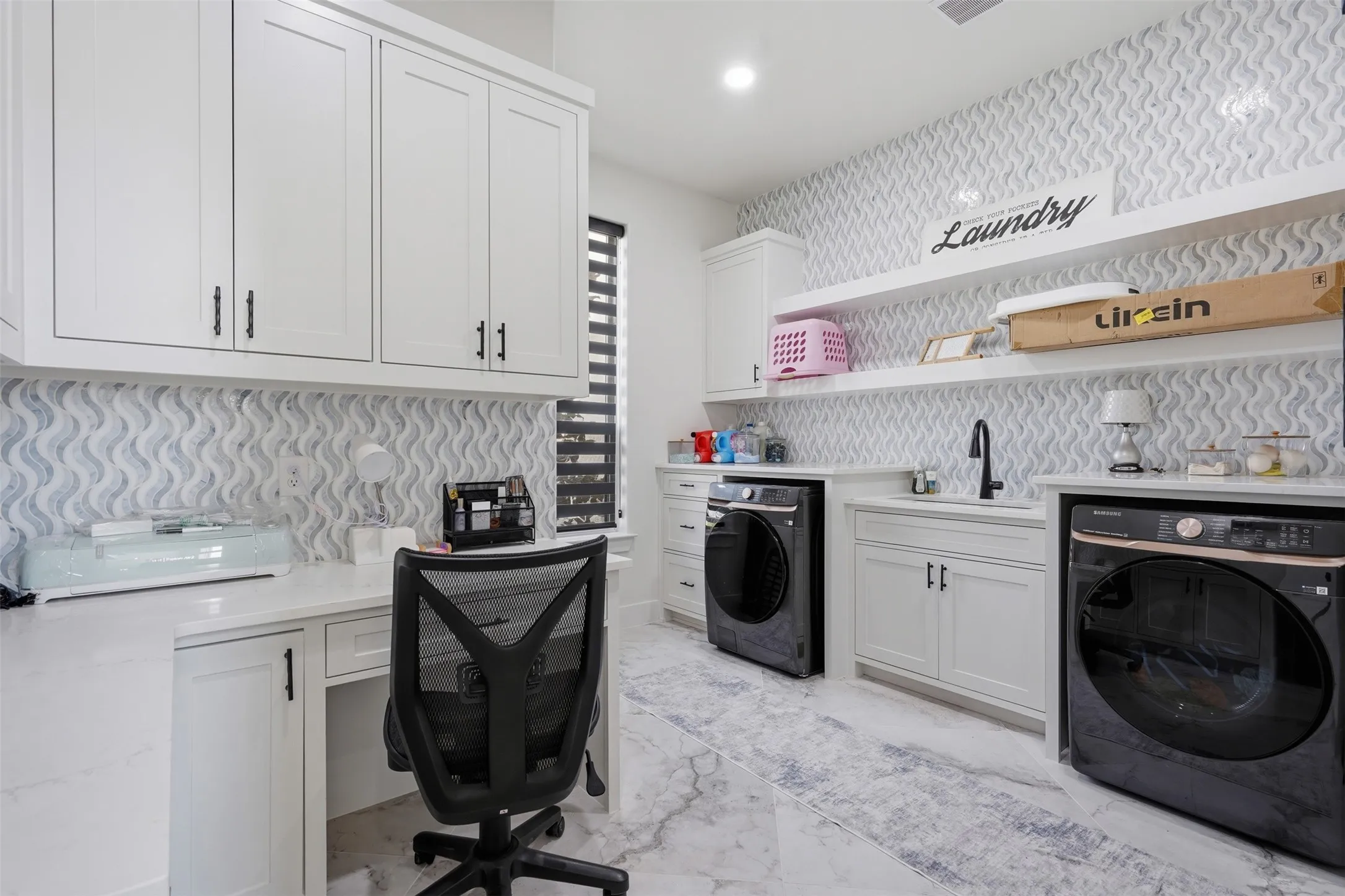 White cabinetry with black hardware, white countertops, pattern tile backsplash, recessed lighting, and a built-in desk
