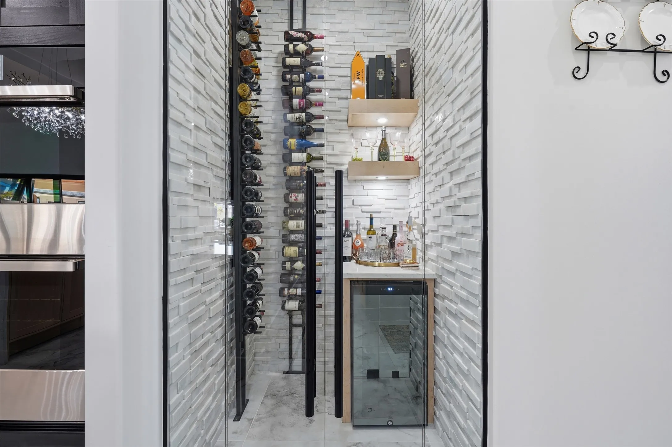 Glass-enclosed wine room with textured stacked stone wall, built-in wine racks, integrated shelving, and a beverage cooler
