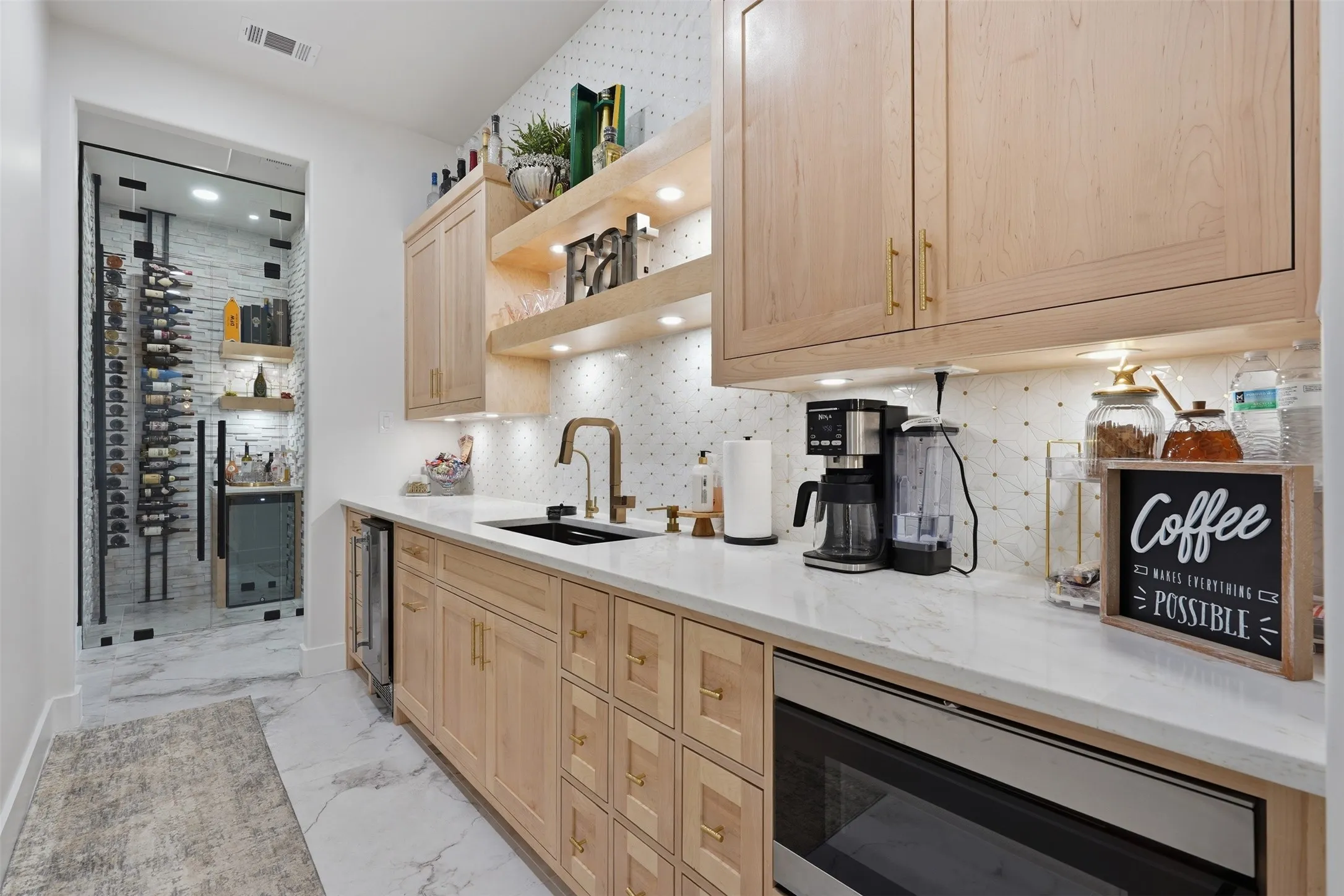 Galley-style kitchen featuring natural wood cabinetry with brass hardware, white quartz countertops, stainless steel appliances including a built-in microwave, and a white subway tile backsplash