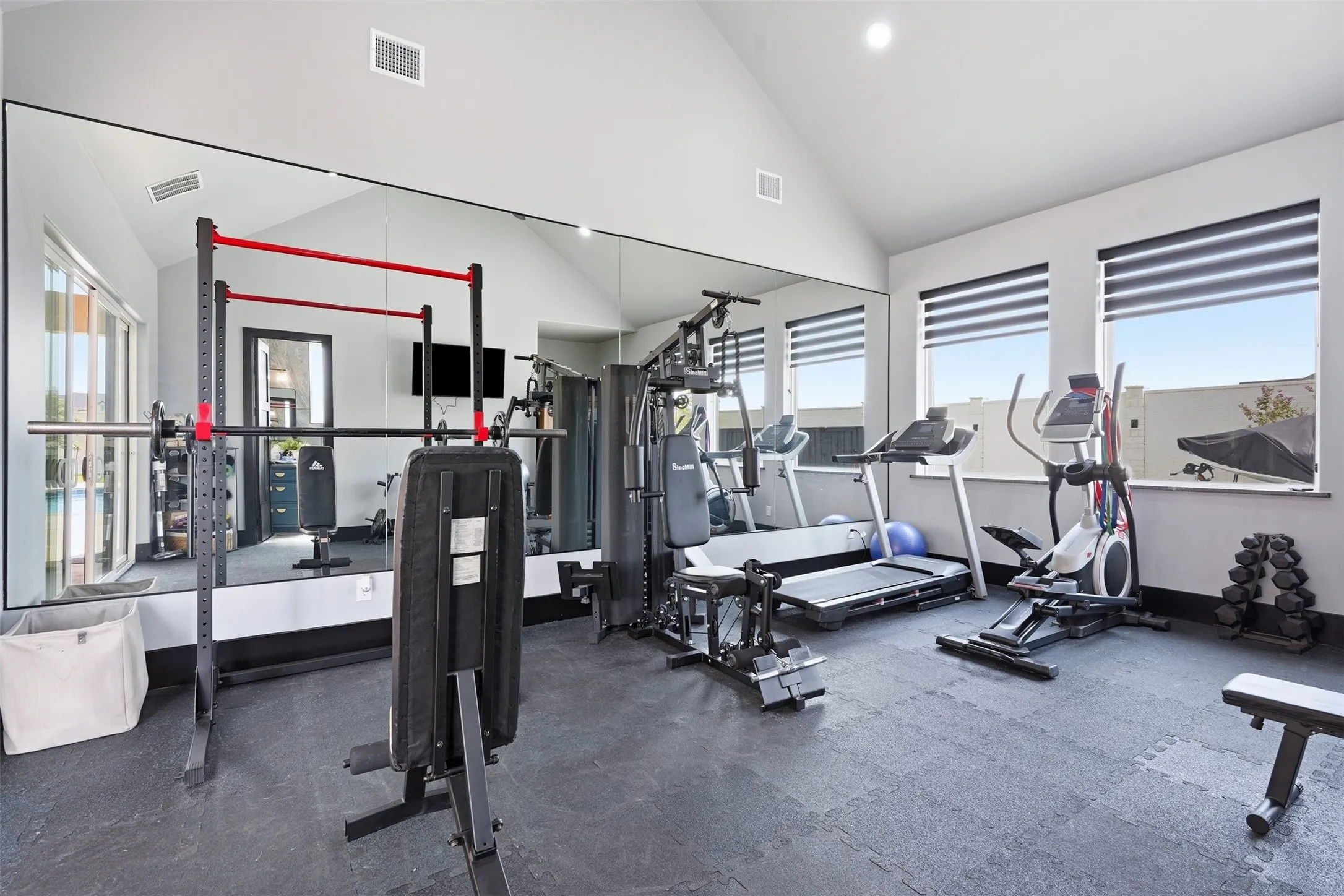 Dedicated fitness space featuring a vaulted ceiling and full-wall mirror
