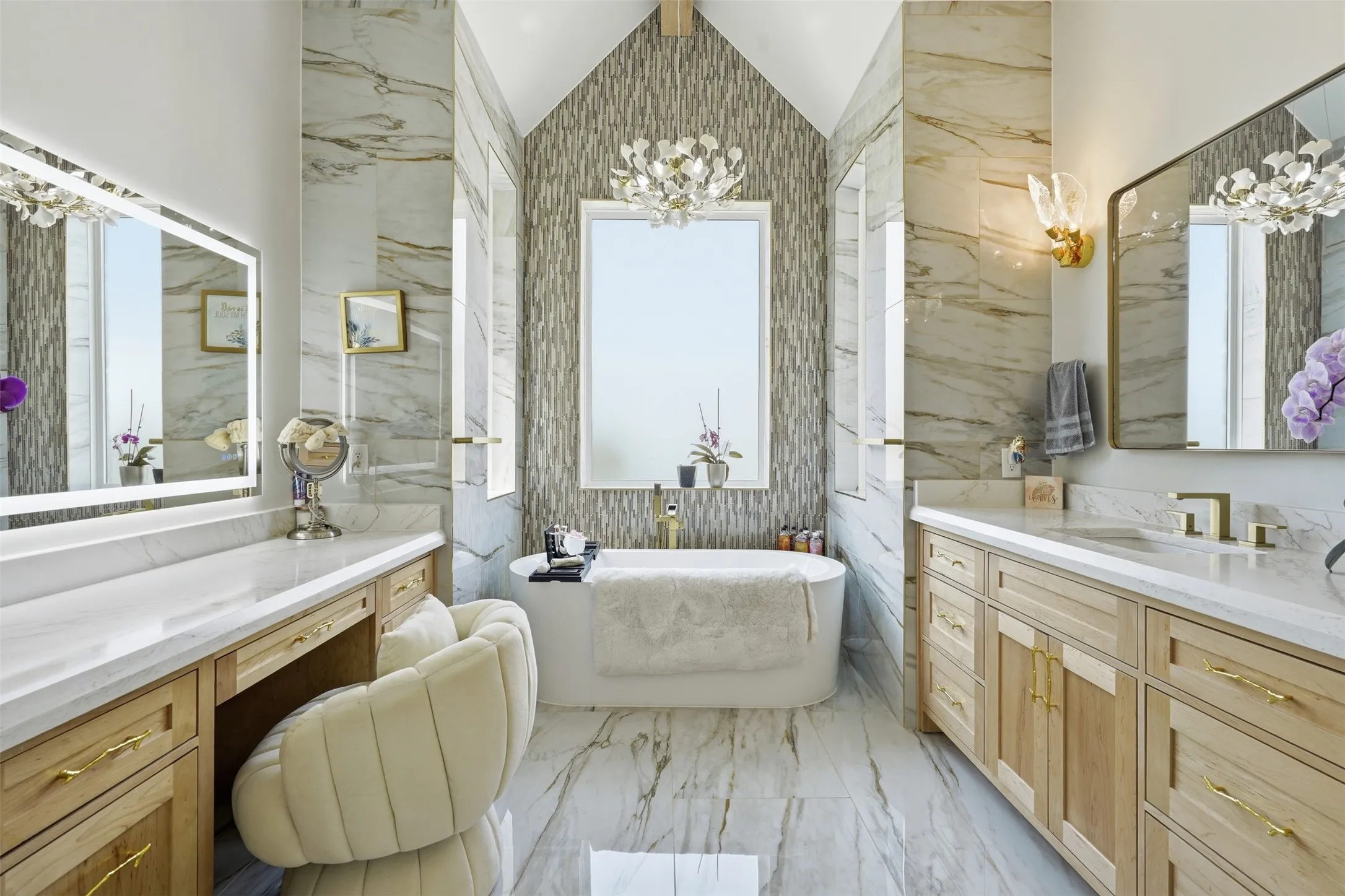 Spa-inspired primary bathroom featuring dual wood-finish vanities with white quartz countertops, a freestanding soaking tub, and a walk-in shower lined with textured stone tile