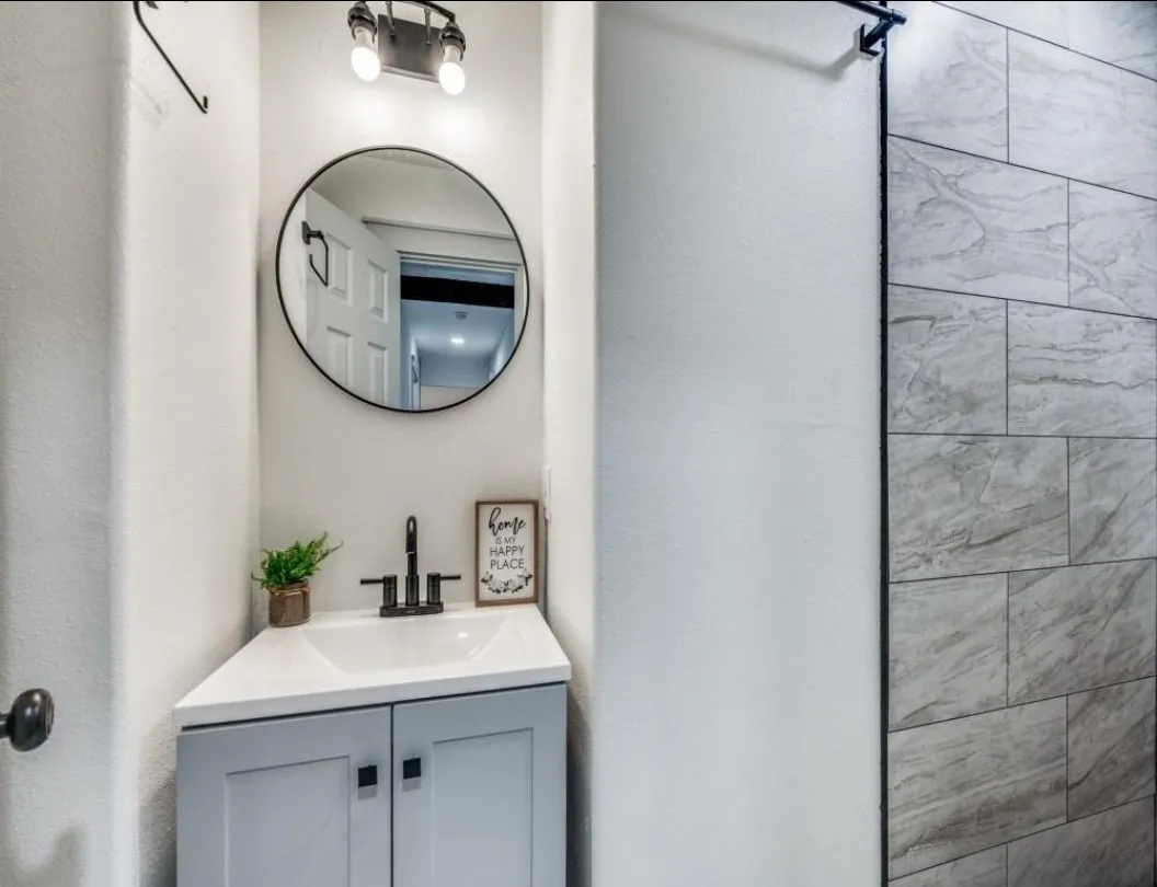 Corner vanity with white countertop, integrated sink, and matte black faucet