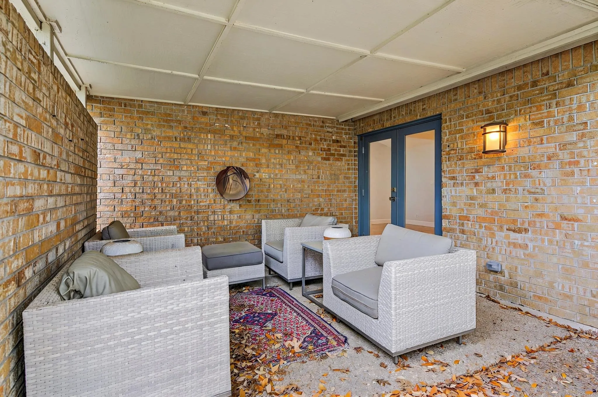 Covered patio area featuring a brick exterior wall, concrete flooring, and a ceiling-mounted light fixture