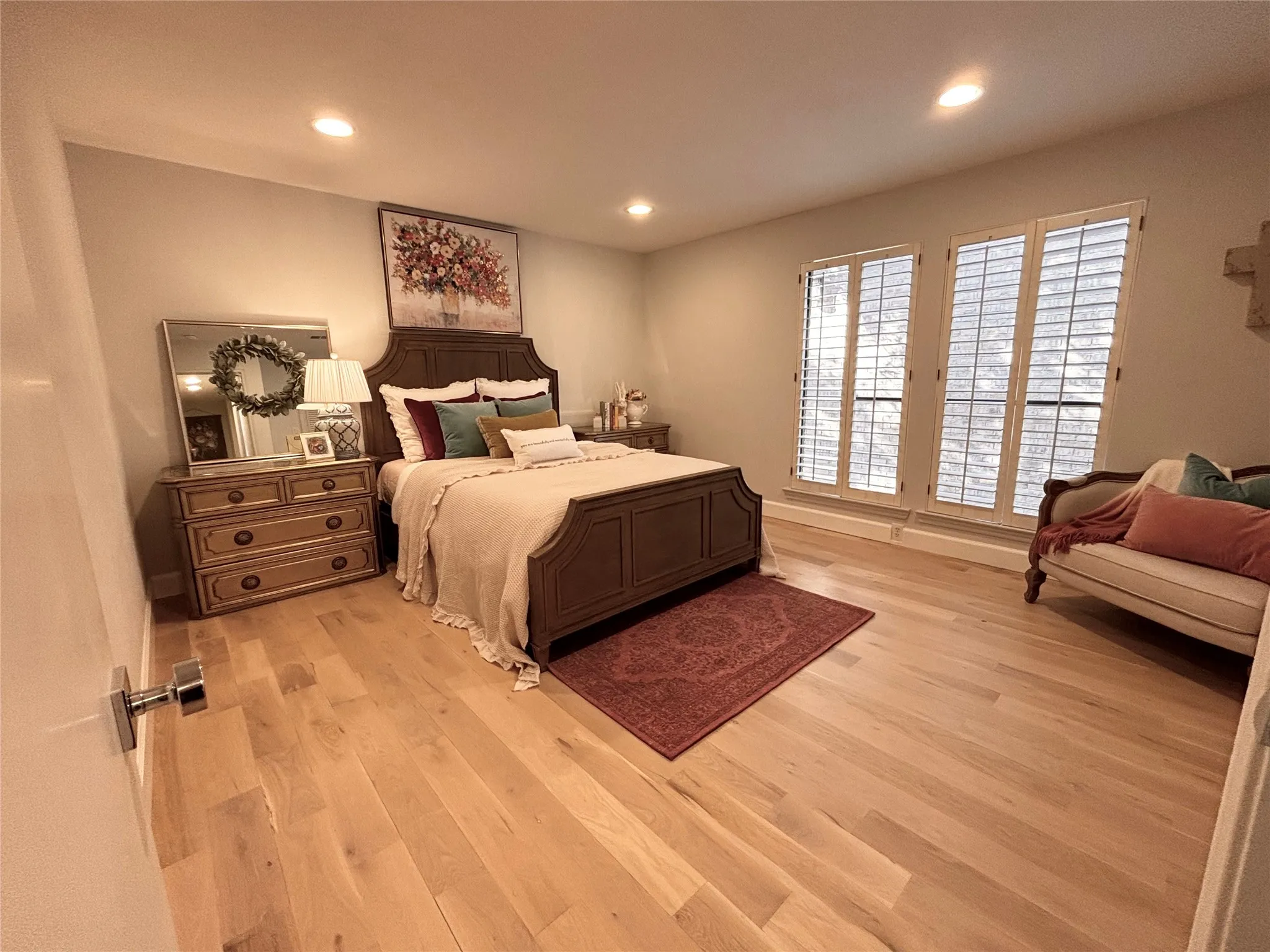 Light wood-finish flooring, recessed ceiling lighting, and two windows with plantation shutters