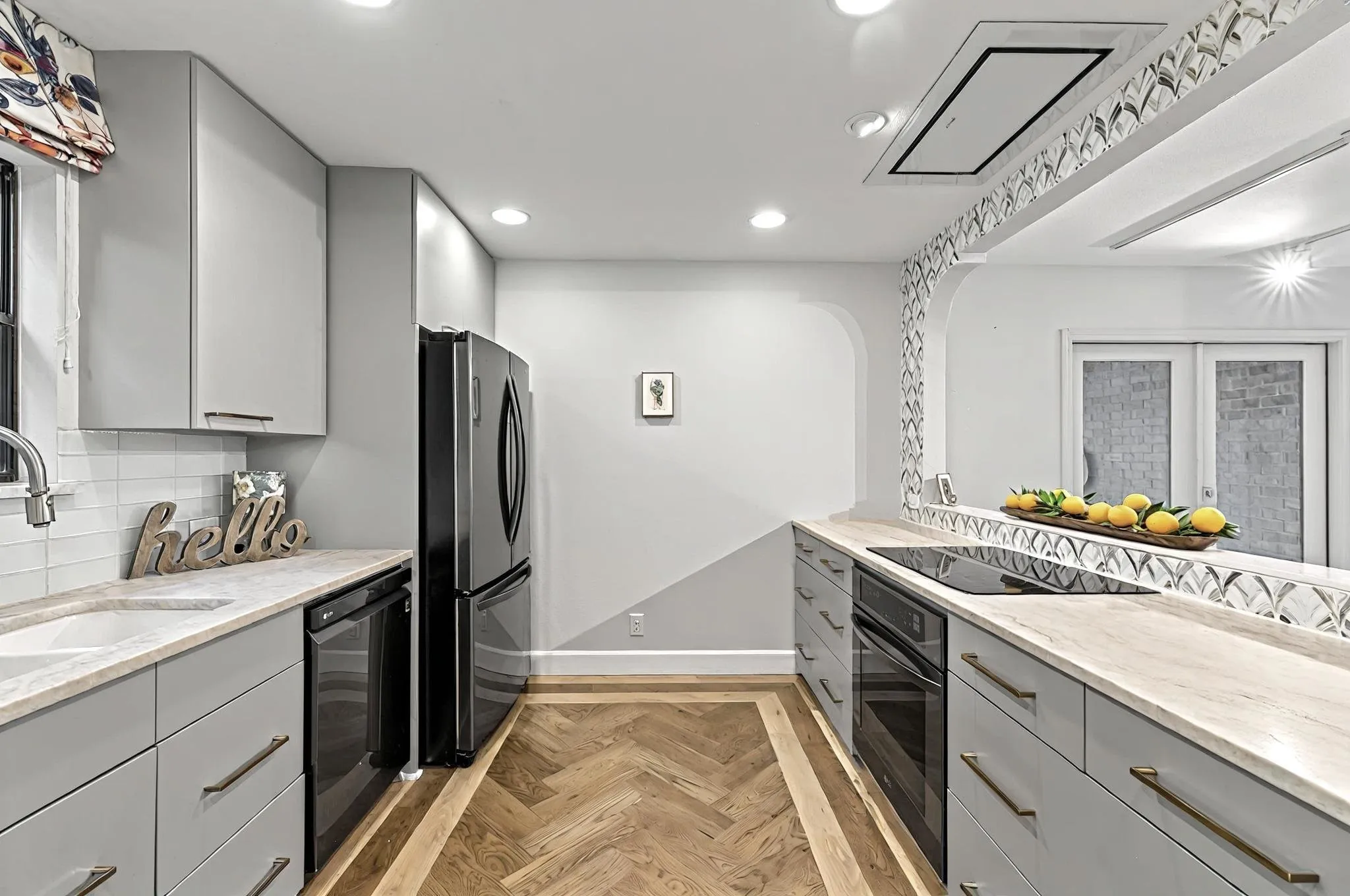 Galley kitchen featuring light gray cabinetry, light-toned countertops, and a herringbone wood-finish floor inlay