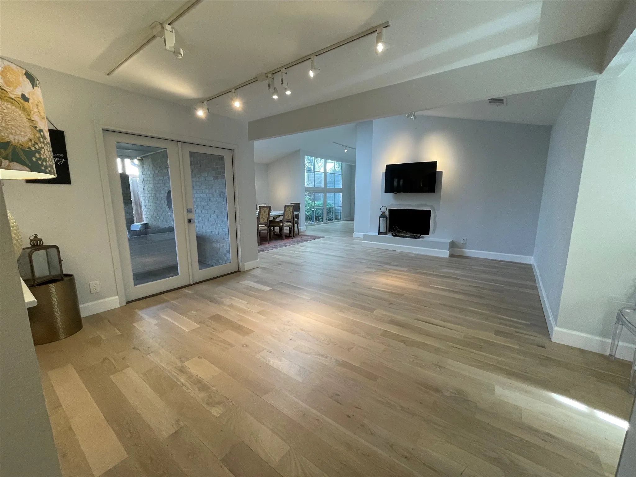 Open-concept living space featuring light wood-finish flooring, recessed lighting, and a built-in media shelf