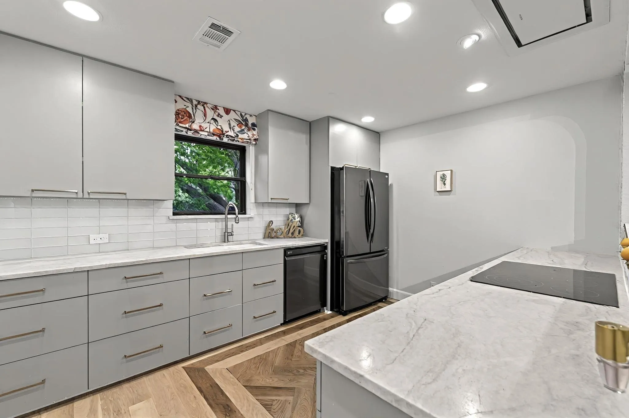 Kitchen featuring light gray cabinetry, light-toned countertops, a white subway tile backsplash, recessed lighting, and wood-finish flooring