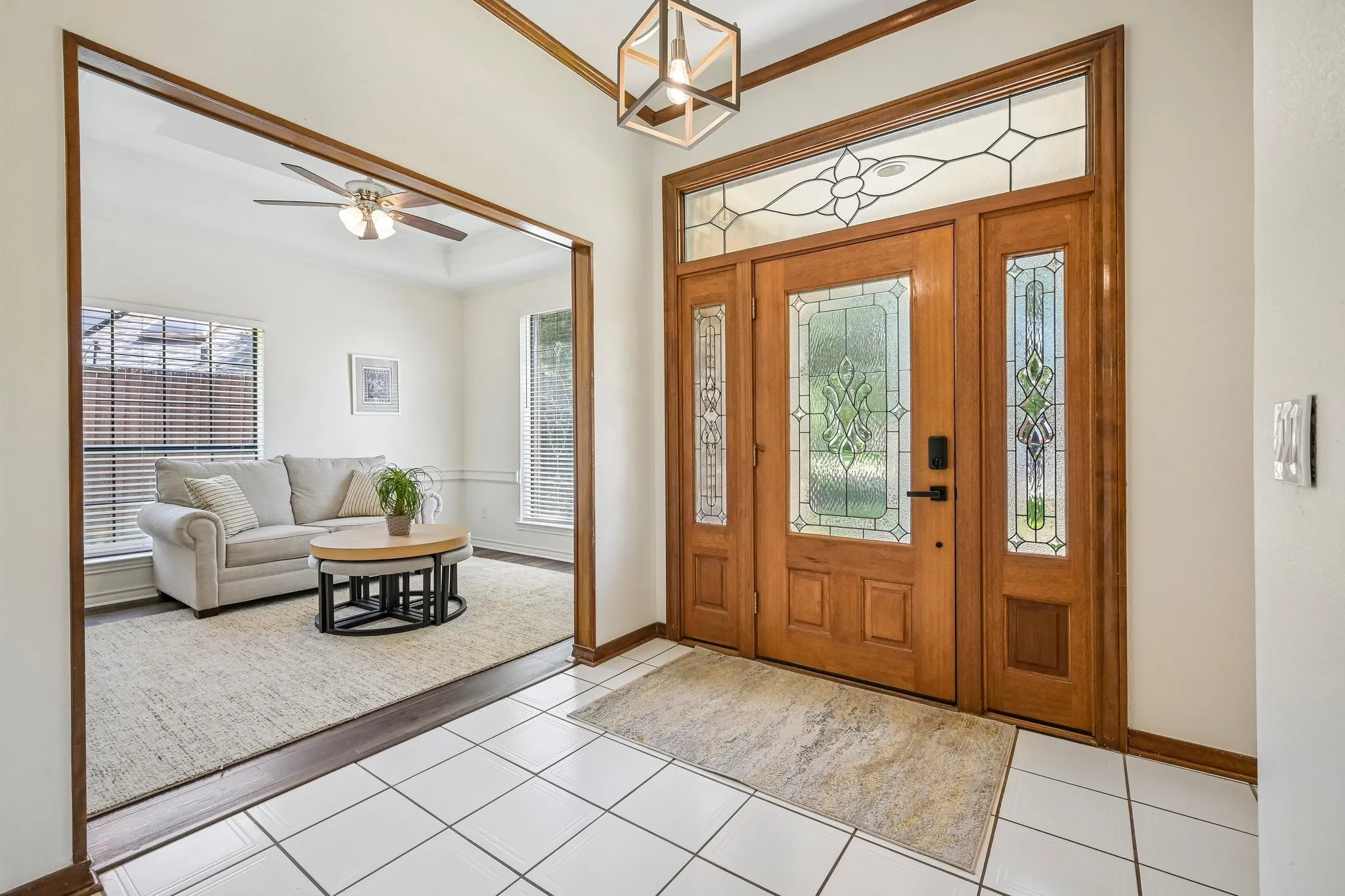 Welcoming foyer featuring solid wood entry doors with decorative glass panels, sidelights, and transom window detailing