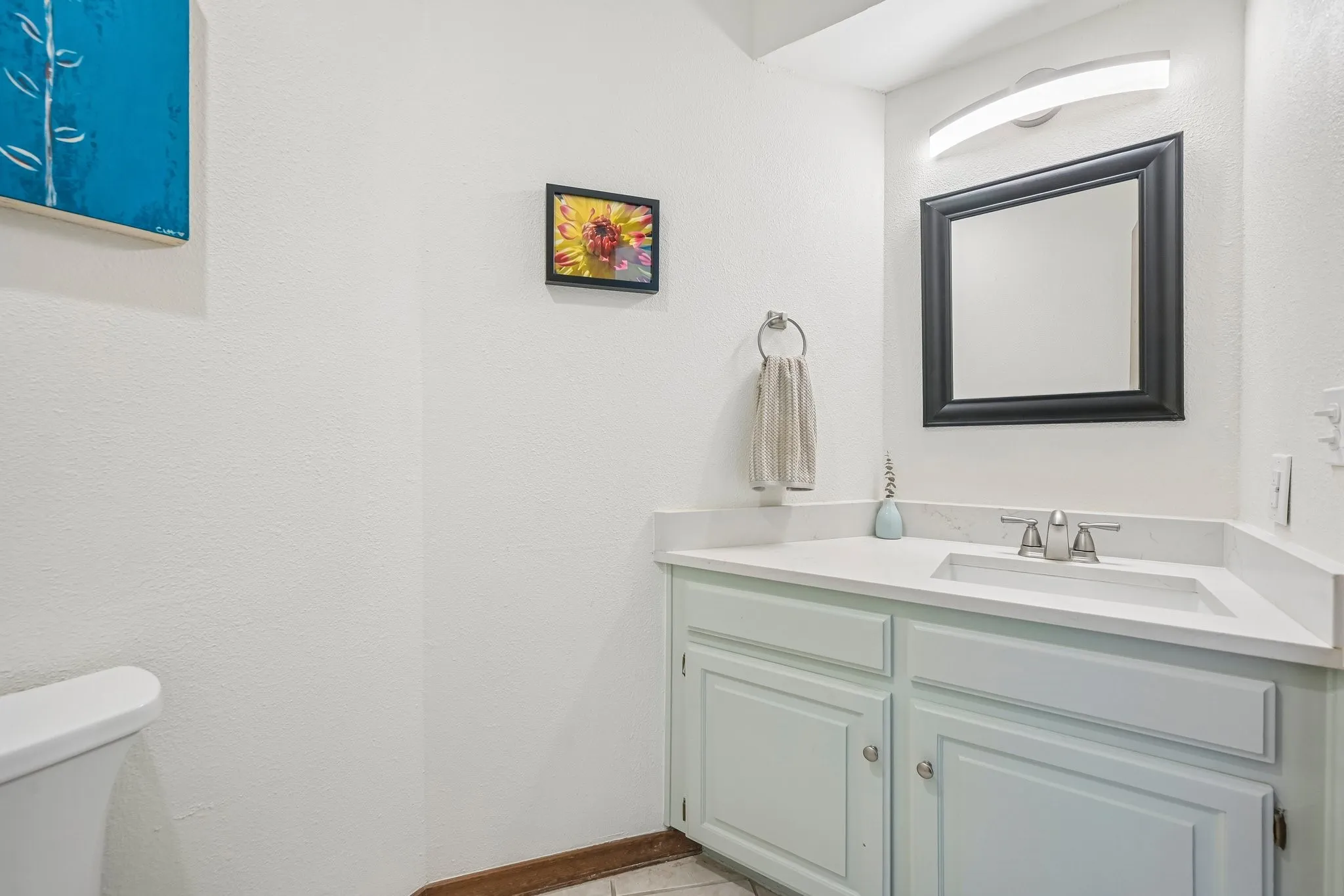 Spa-inspired bathroom featuring a soft sage-green vanity with dual cabinet doors, white quartz countertop, and chrome widespread faucet