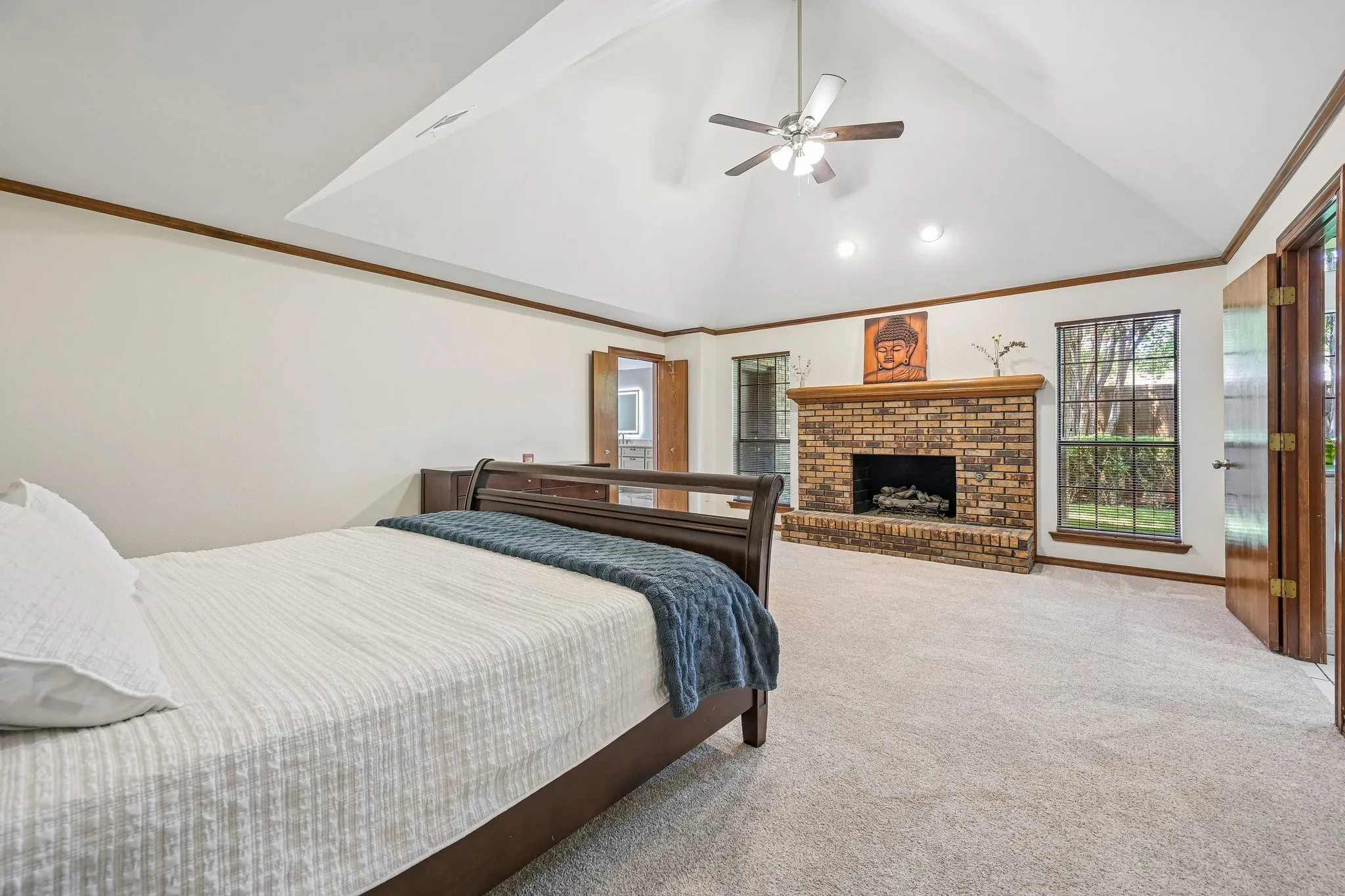 Vaulted ceiling with a ceiling fan, brick fireplace, and dual windows