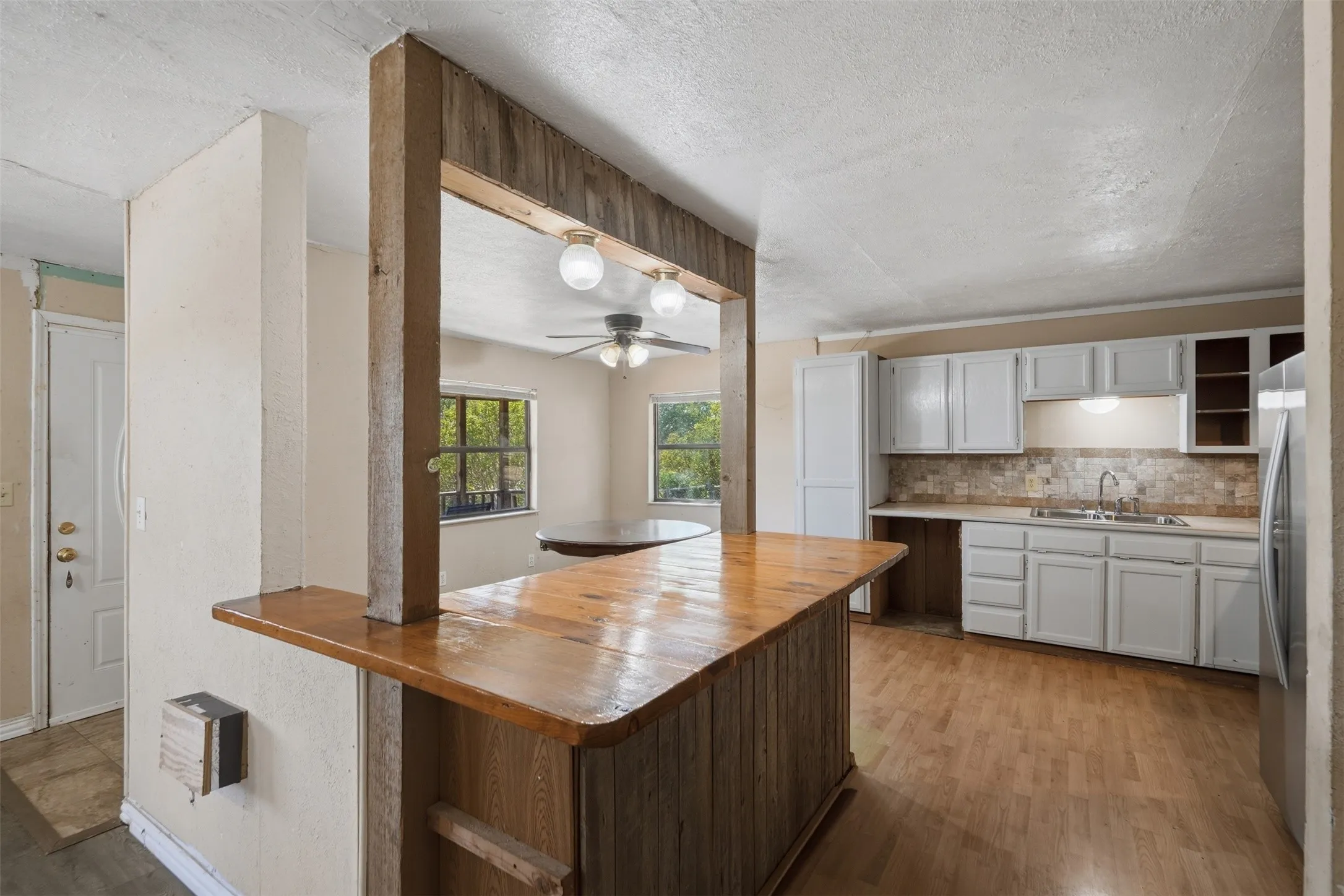 Kitchen featuring white cabinetry, a neutral-toned tile backsplash, and a stainless steel refrigerator
