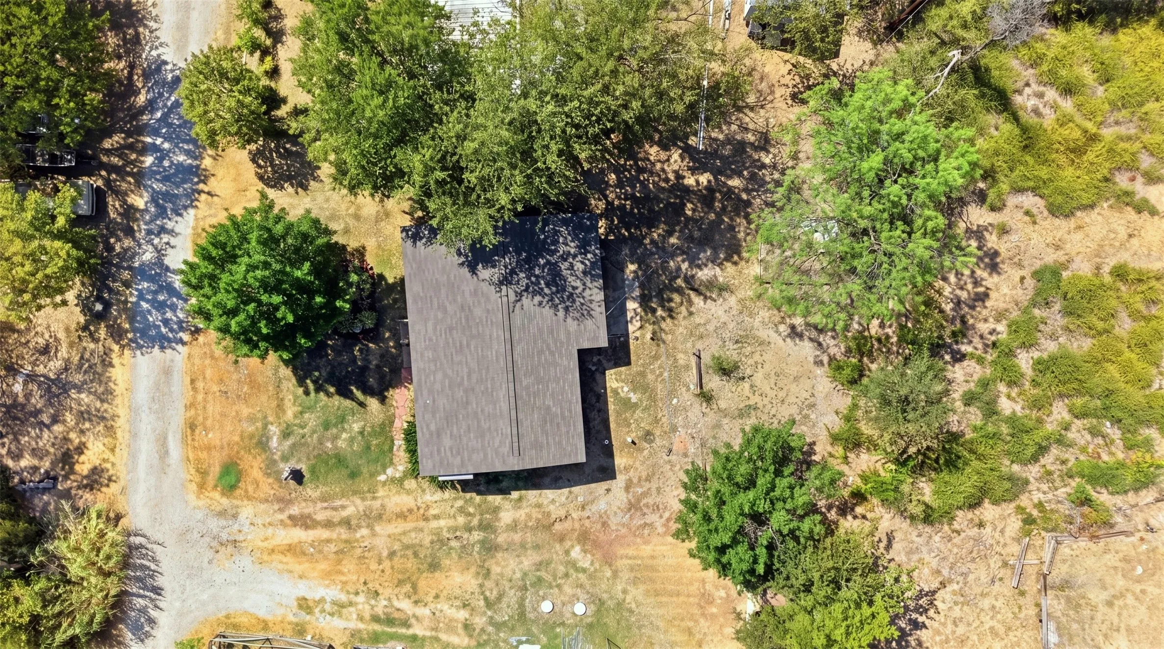 Gabled roofline property with surrounding mature trees and a gravel driveway