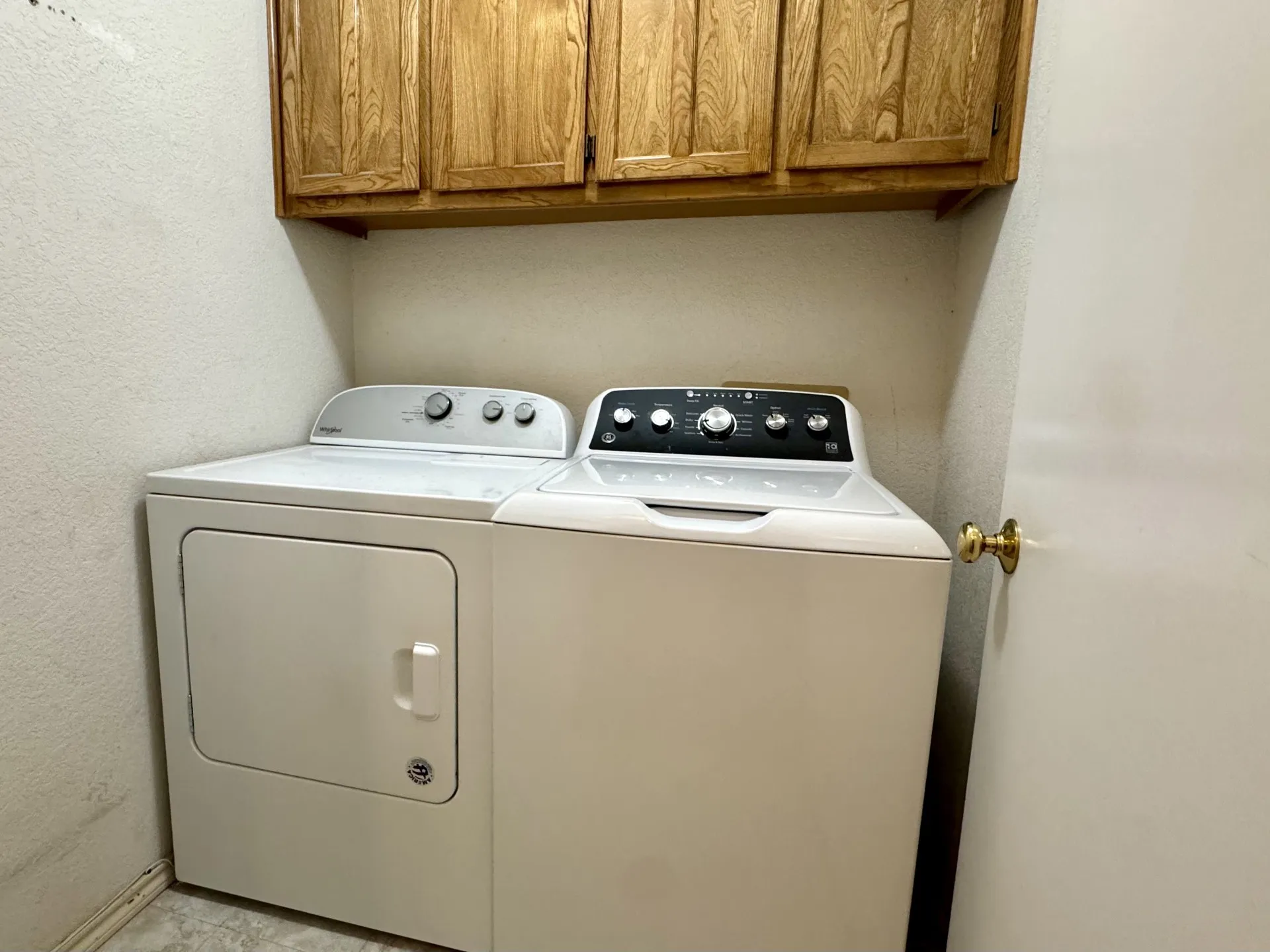 Dedicated laundry room is between Primary BR and garage: features side-by-side washer-dryer and custom wood cabinetry for storage above.