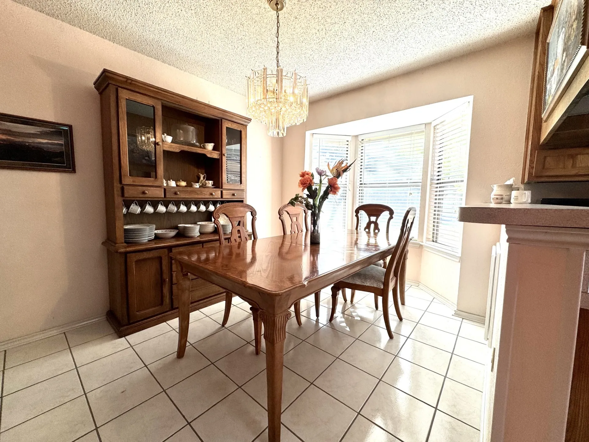 Dining: ceramic tile flooring, multi-paned bay windows, and a crystal chandelier.