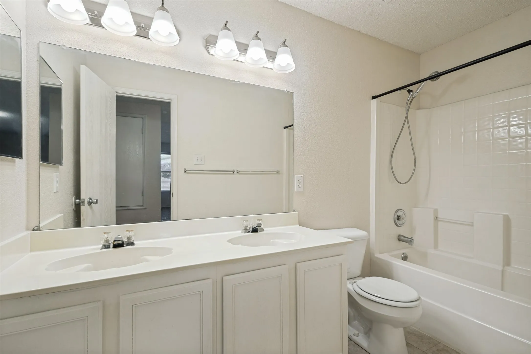 Dual vanity with integrated sinks, white cabinetry, and a full-width mirror with overhead lighting