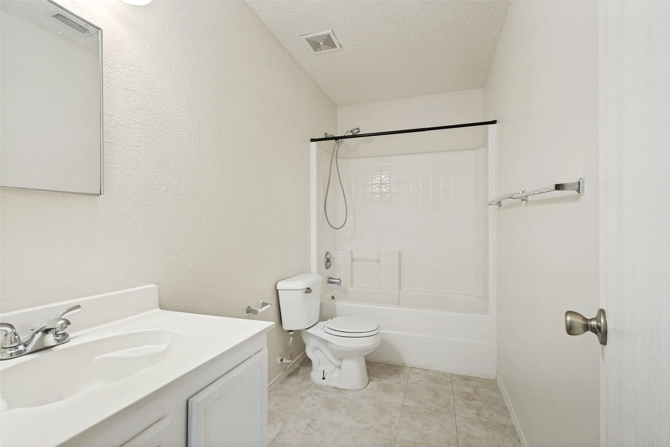 Bathroom featuring a white vanity with an integrated sink, chrome faucet, wall-mounted medicine cabinet, white toilet, and a white bathtub with a shower kit