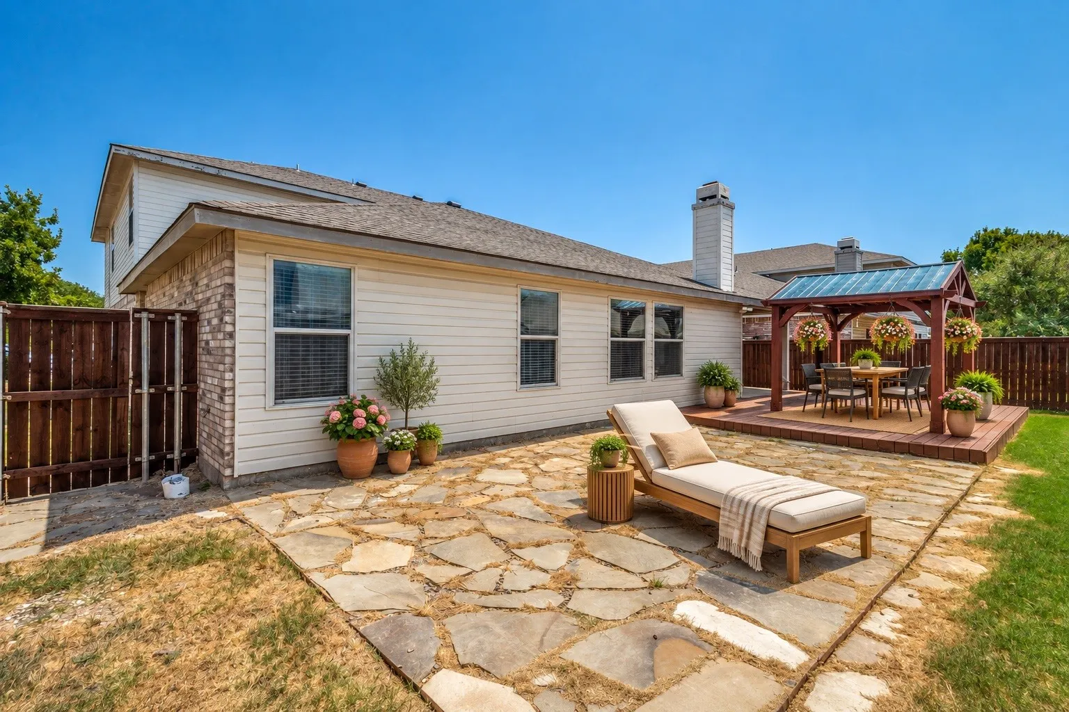 Expansive flagstone patio area with a built-in pergola and a raised wood deck