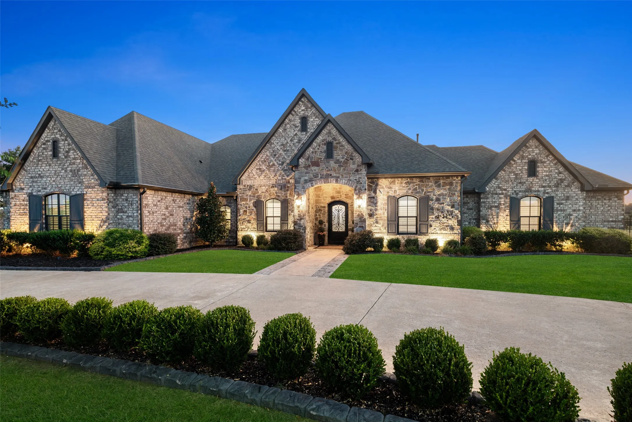 Stone exterior with arched entry, gabled roofline, and landscaped grounds