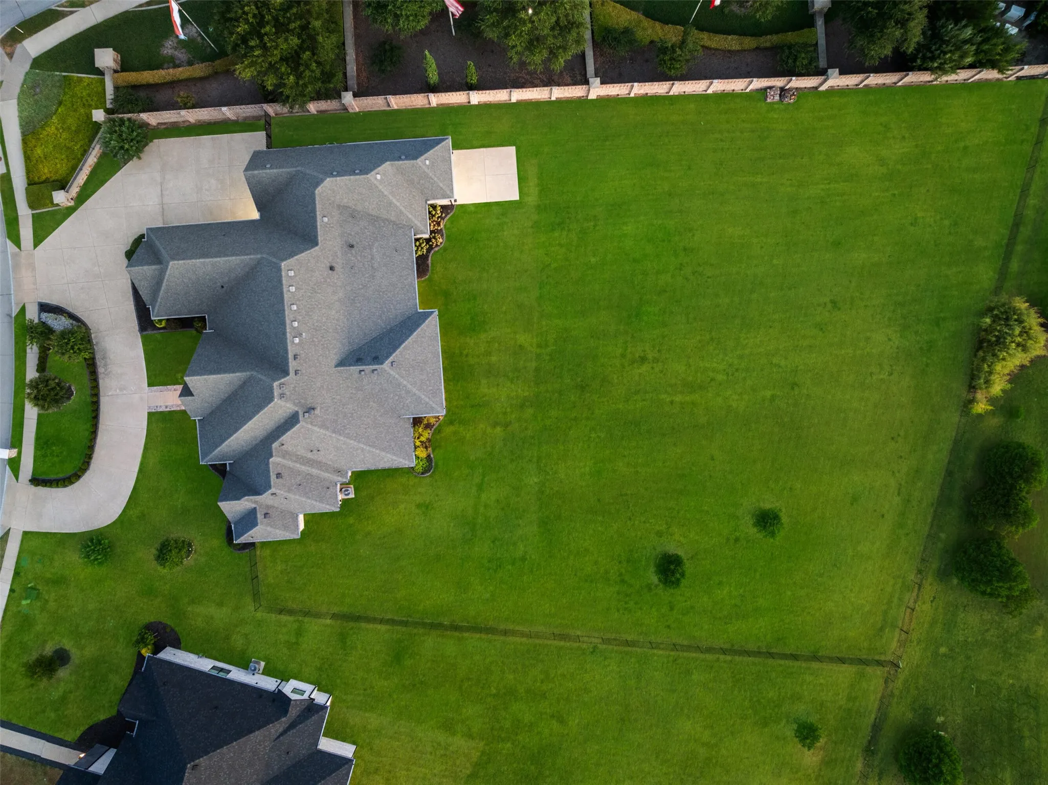 Expansive lot featuring a large residence with a multi-gabled roof, a substantial paved driveway, and a broad green lawn