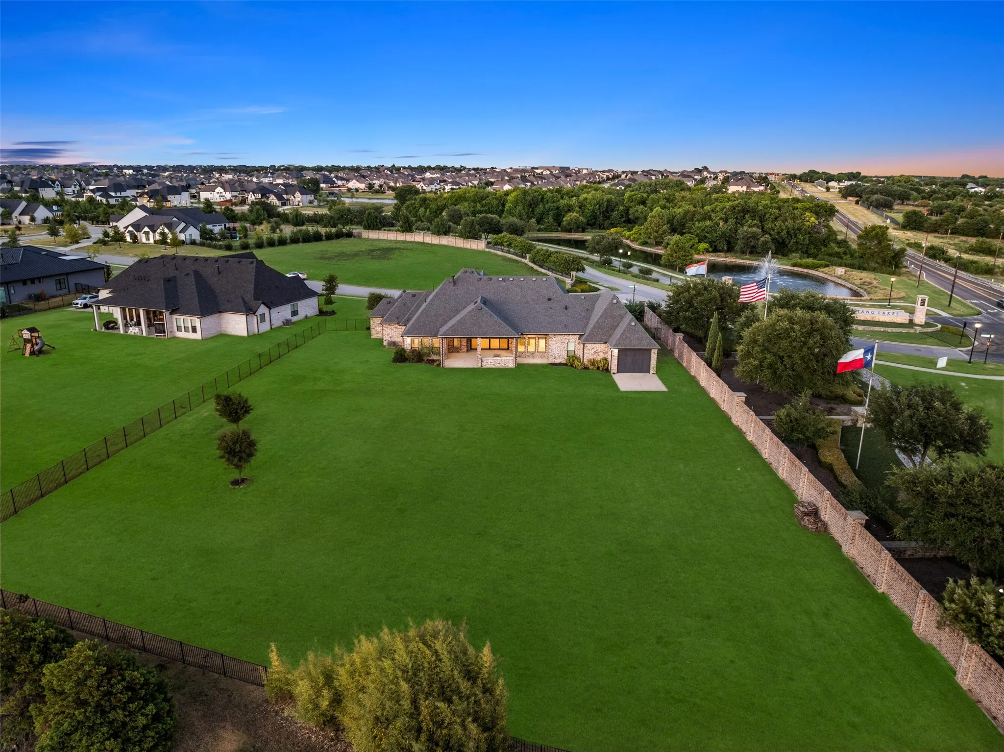 Expansive green lawn surrounding a stone exterior residence with an attached garage