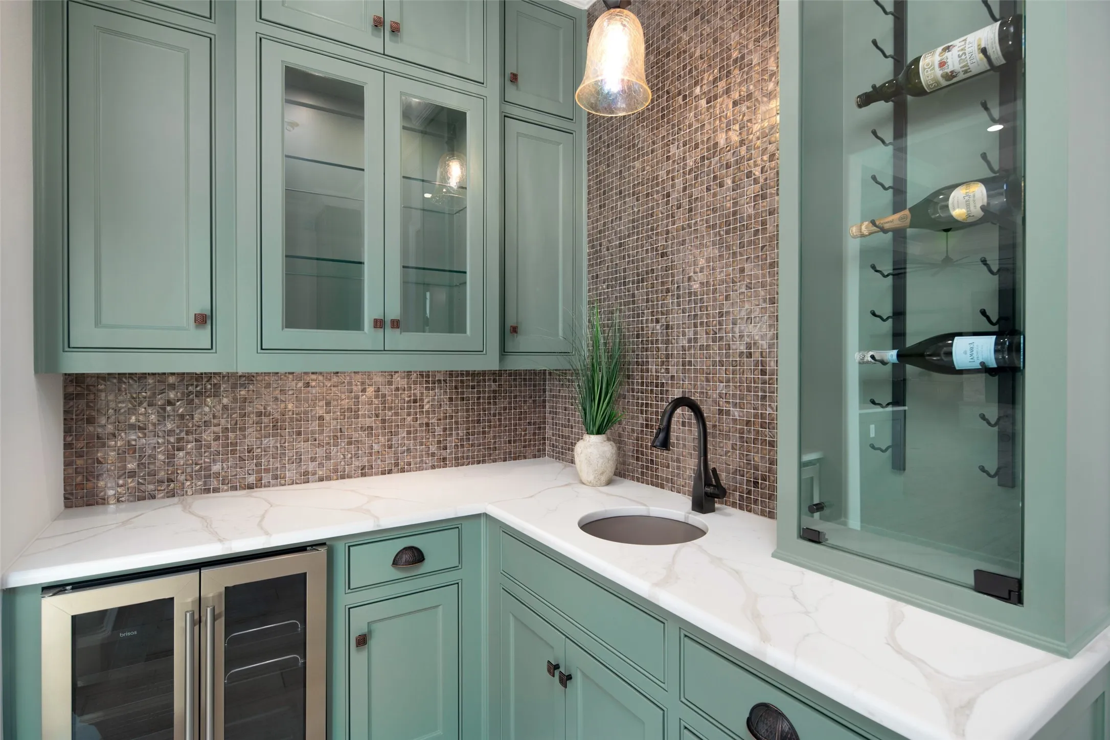Custom cabinetry with glass-front uppers, mosaic tile backsplash, integrated beverage cooler, and built-in wine storage