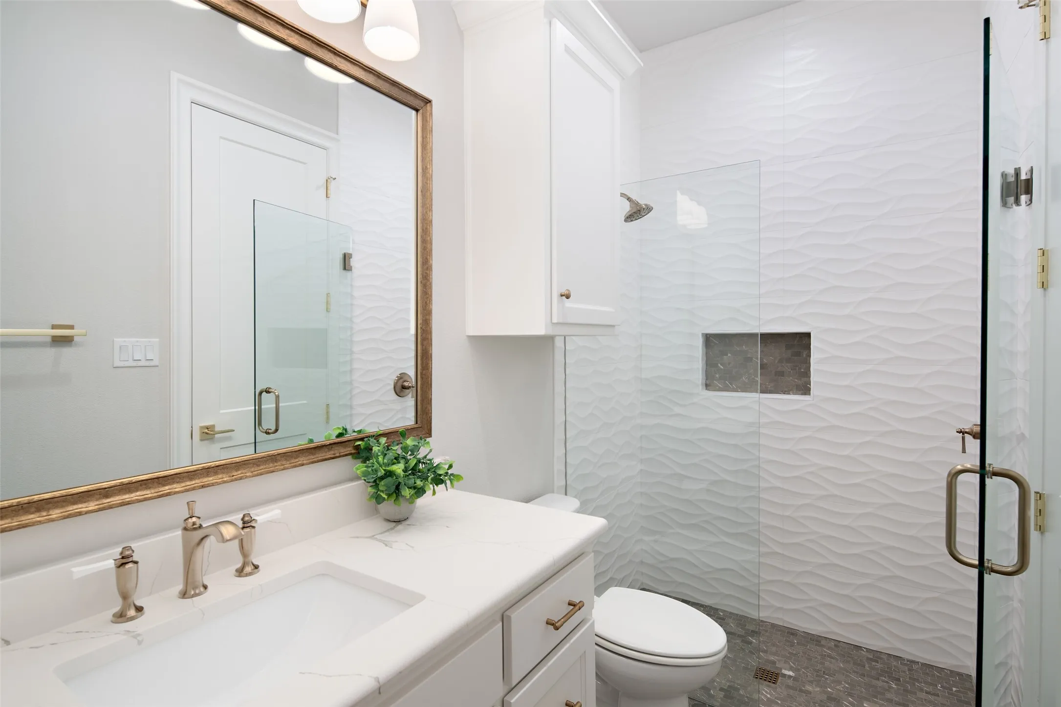 Quartz countertop vanity with a rectangular undermount sink, brushed nickel faucet, and a gold-framed mirror