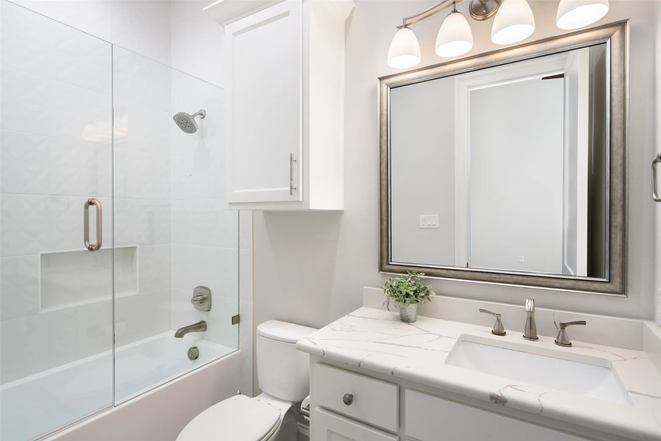 White vanity with a stone countertop, an undermount sink, and a framed mirror