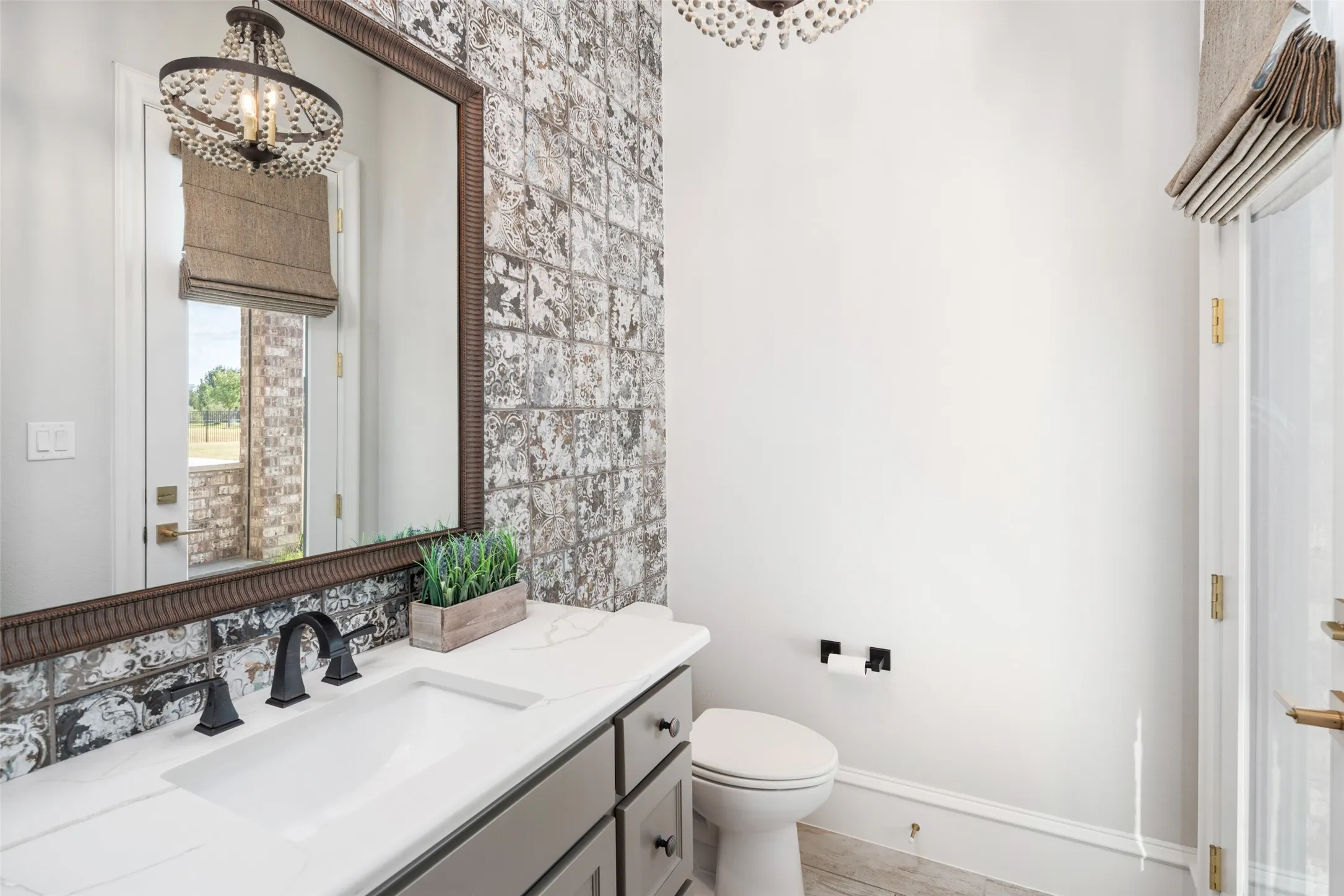 Vanity with integrated sink and dark-toned faucet, decorative wall tile, and a framed mirror
