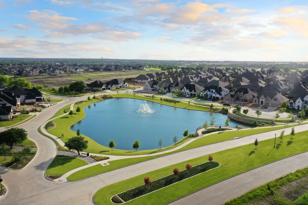 Community featuring a central pond with fountain, surrounding green spaces, paved pathways, and an array of residential properties