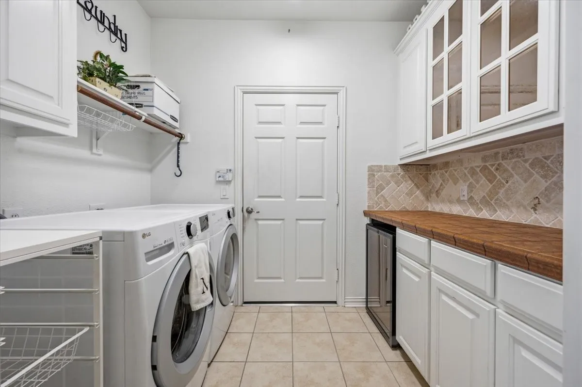 Lots of additional storage with glass front cabinets, wine refrigerator, lower roll out cabinet,  plus shelving  and a cabinet above  the washer and dryer area - - door to the garage