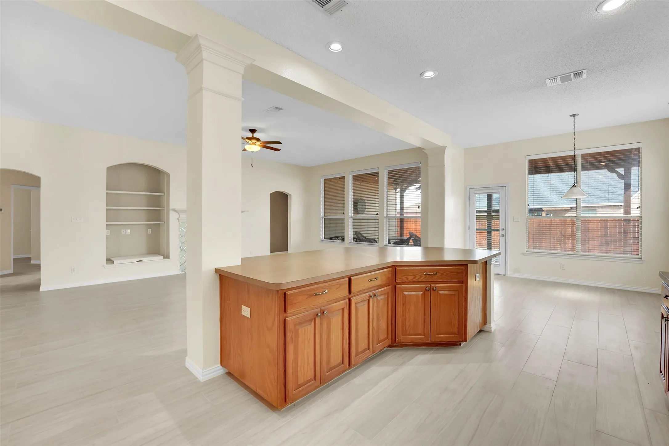 Open-concept kitchen and great room featuring a wood-finish island with ample counter space, rich cabinetry, recessed ceiling lighting, and ceiling fan