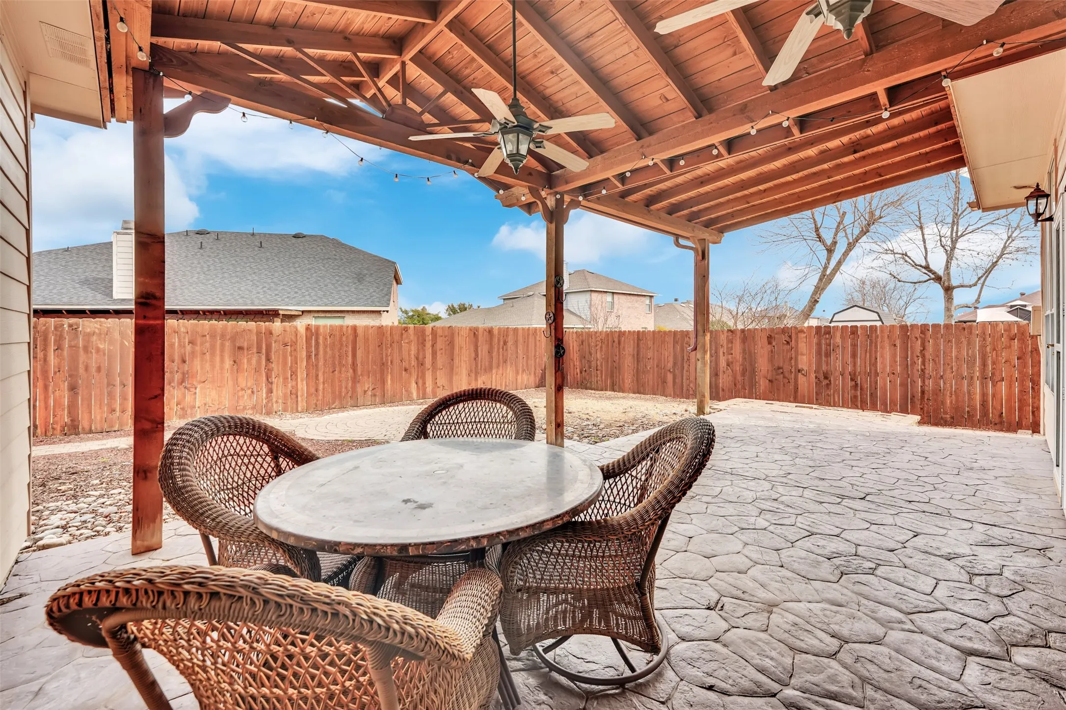 Covered patio with an exposed wood beam ceiling, dual ceiling fans, and string lighting