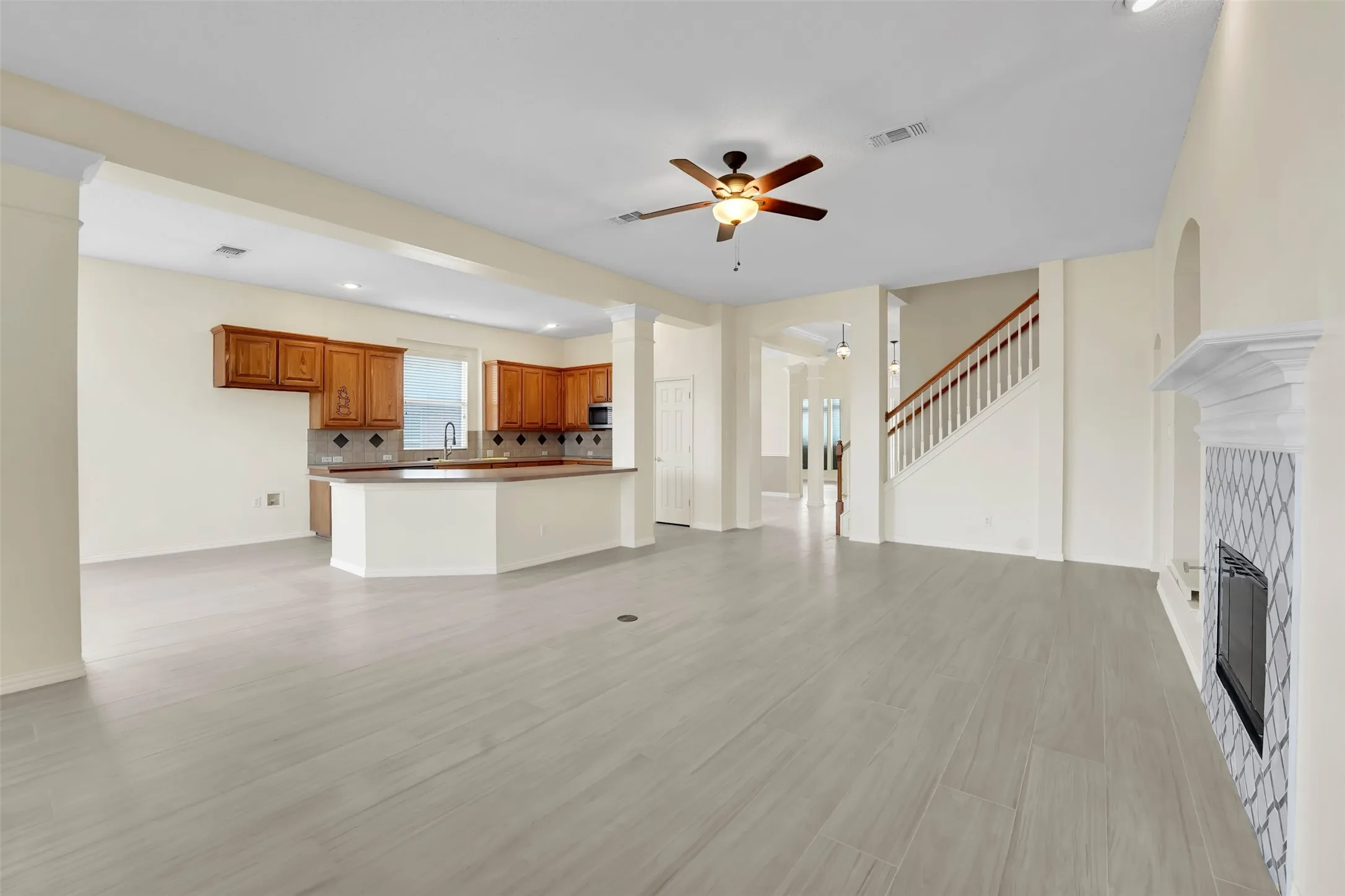Open-concept living area with wood-finish flooring throughout, recessed ceiling lighting, and a ceiling fan