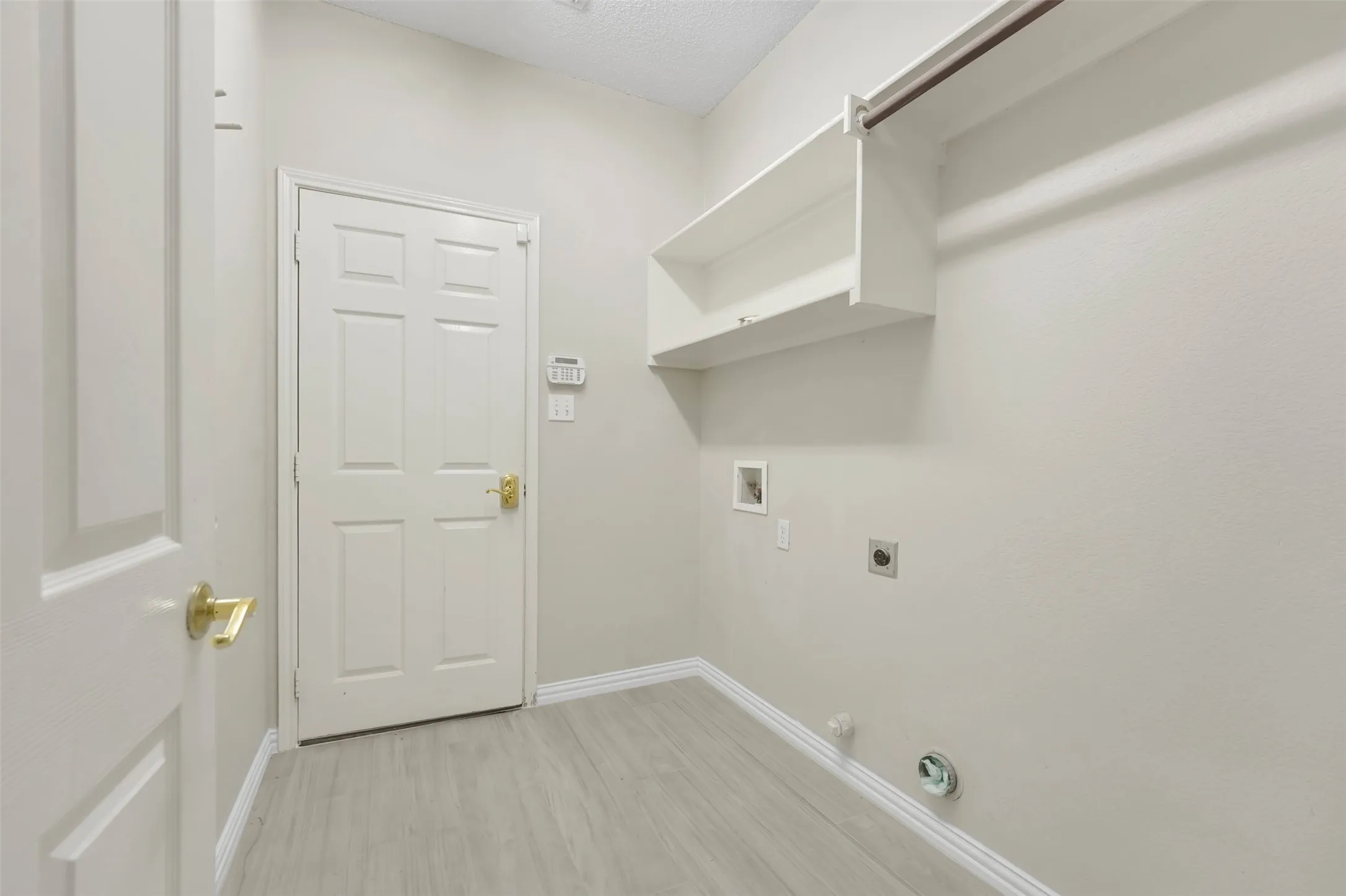 Utility room featuring wood-finish flooring, built-in shelving, and a hanging rod
