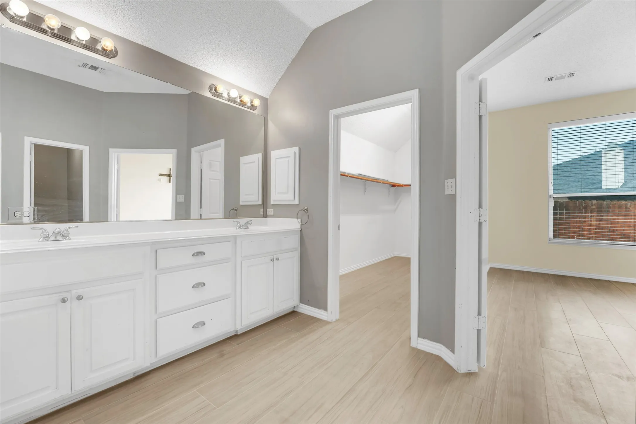 Spa-inspired primary bathroom featuring an expansive double-vanity with white cabinetry, brushed nickel hardware, and integrated sink basins